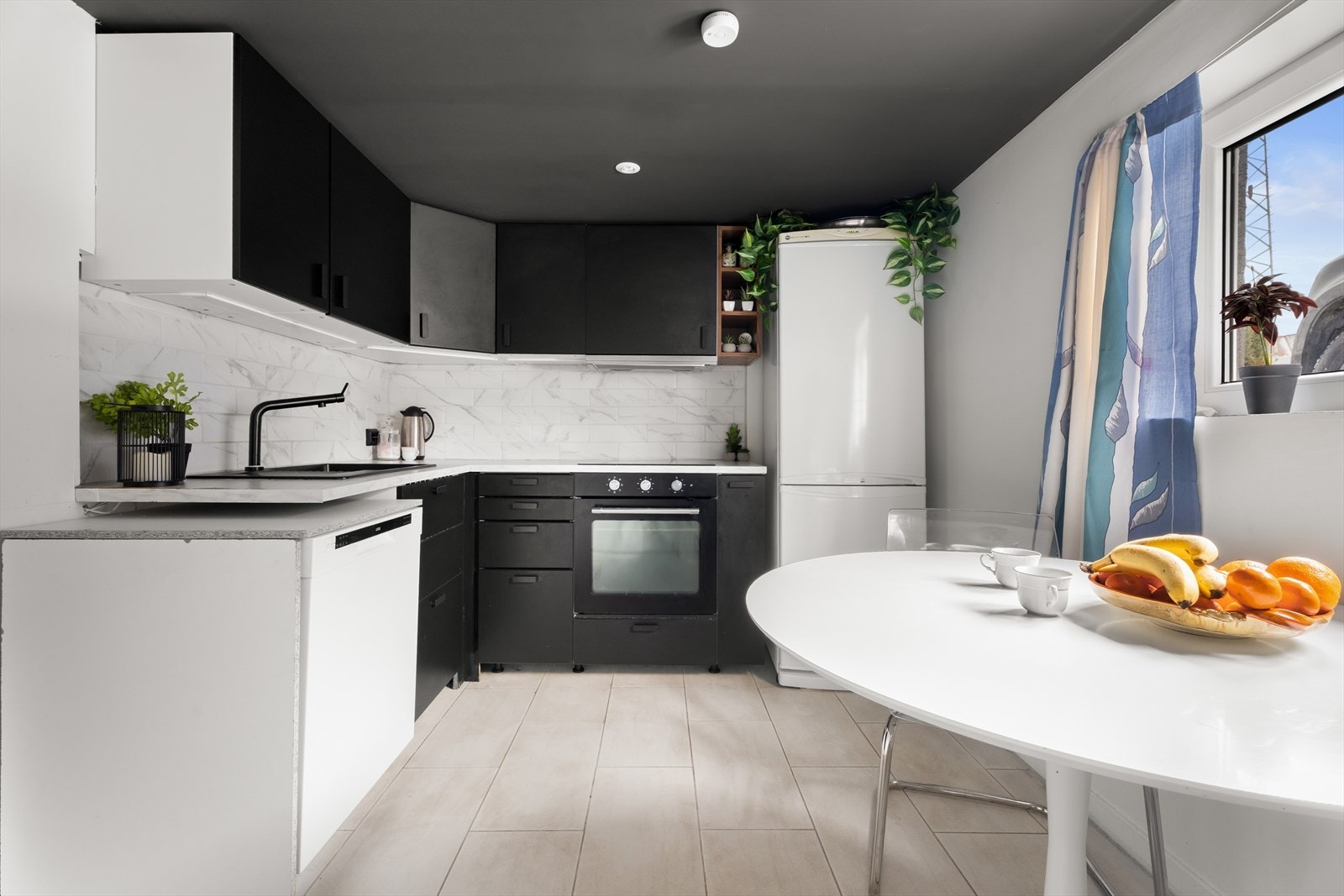 Flott kjøkken med moderne detaljer innredet med slette fronter, laminert benkeplate og flott sort oppvaskkum. Galleribilde