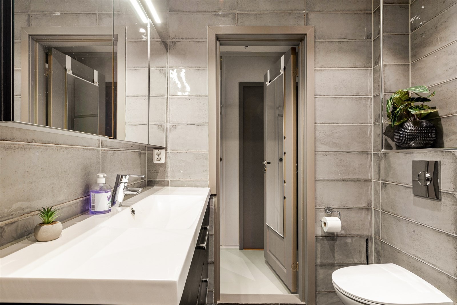 Stilrent bad med moderne fliser, romslig servantløsning og vegghengt toalett. God oppbevaring og praktiske detaljer gir et funksjonelt og helhetlig uttrykk. Galleribilde