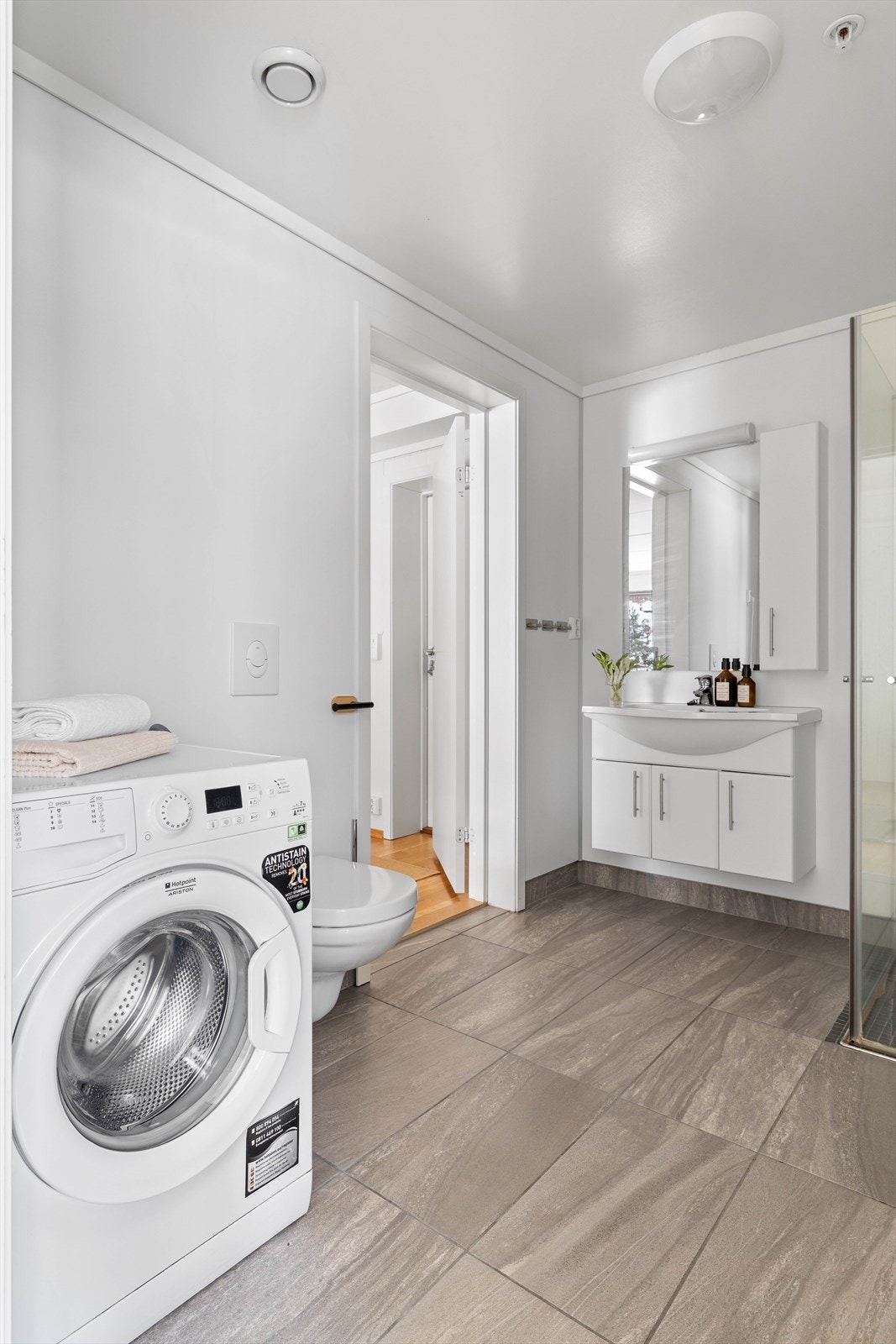 Badet er fra byggeår i 2016 og er innredet med veggmontert toalett, dusjvegger/hjørne og innredning med nedfelt servant. Det er også opplegg for vaskemaskin Galleribilde