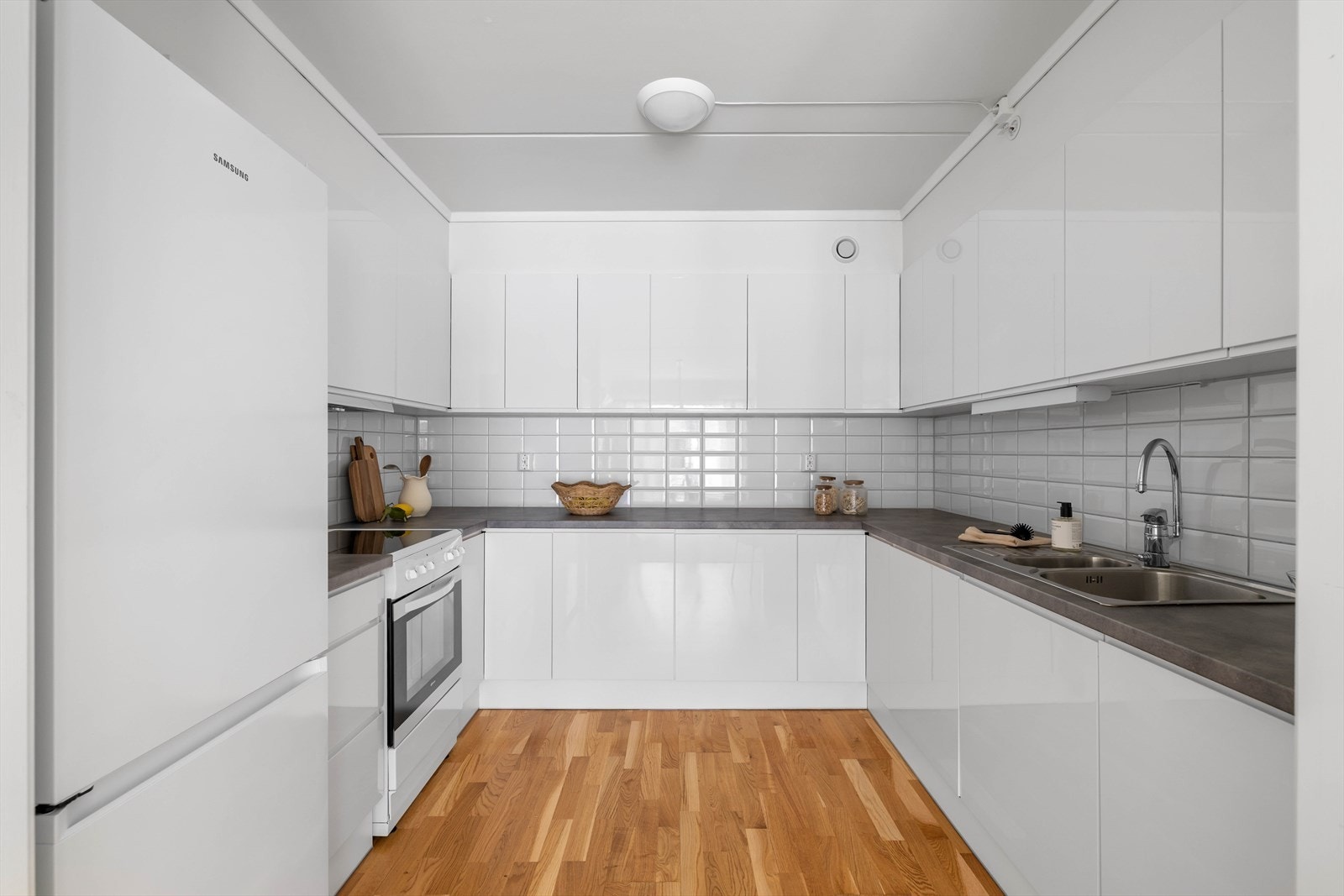 Lys og pent kjøkken med lyse glatte fronter og benkeplate av laminat. Av integrerte hvitevarer er det kjøl/fryseskap, oppvaskmaskin, komfyr og induksjonstopp Galleribilde