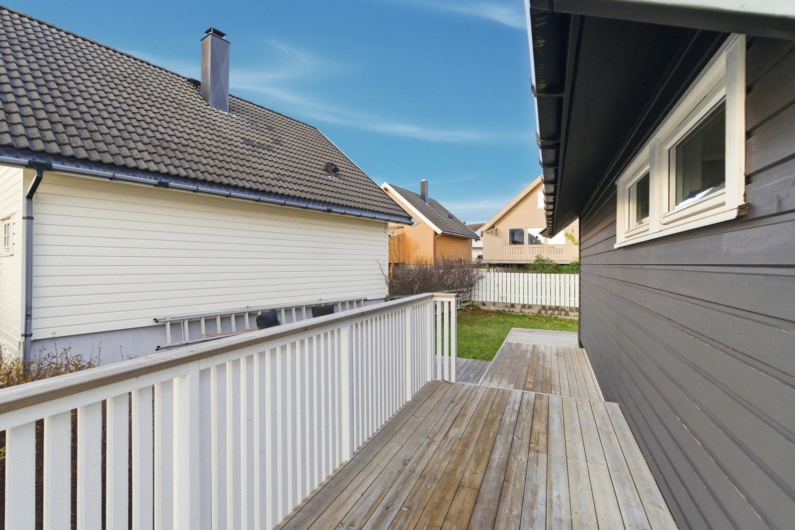 Veranda som strekker seg rundt boligen, ned til terrasse og hage Galleribilde