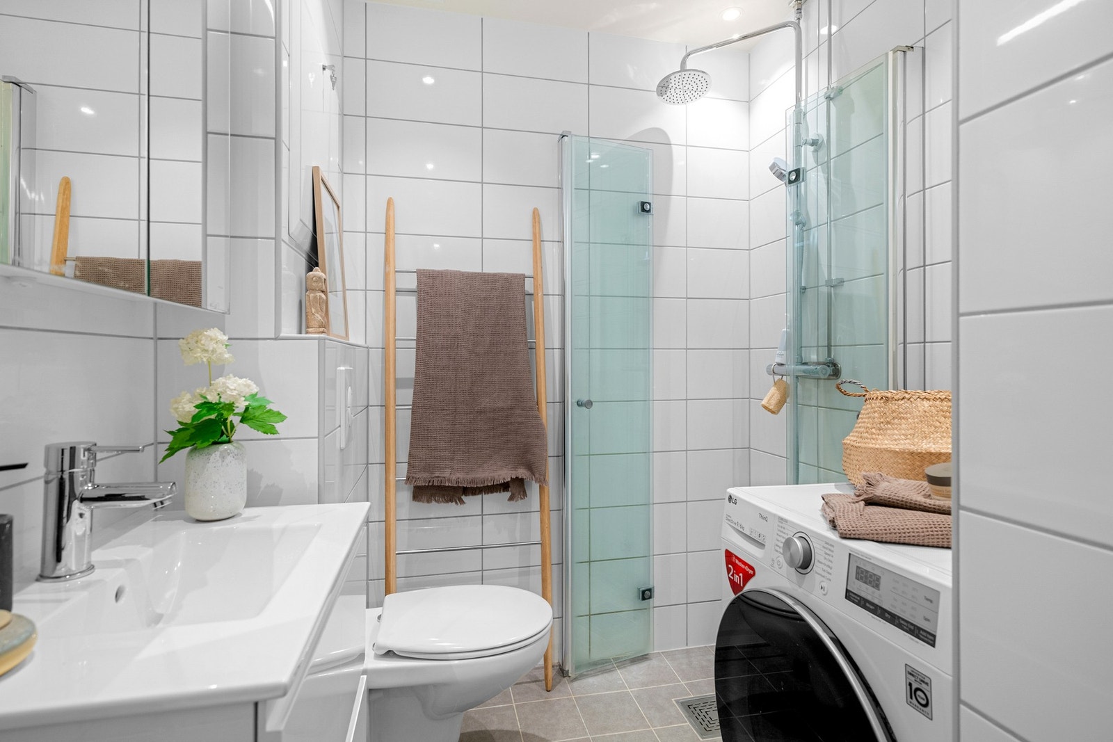 Baderommet er også utstyrt med dusjhjørne med innfellbare glassdører og både hånd- og regnfallsdusj, vegghengt toalett og opplegg for vaskemaskin. Galleribilde