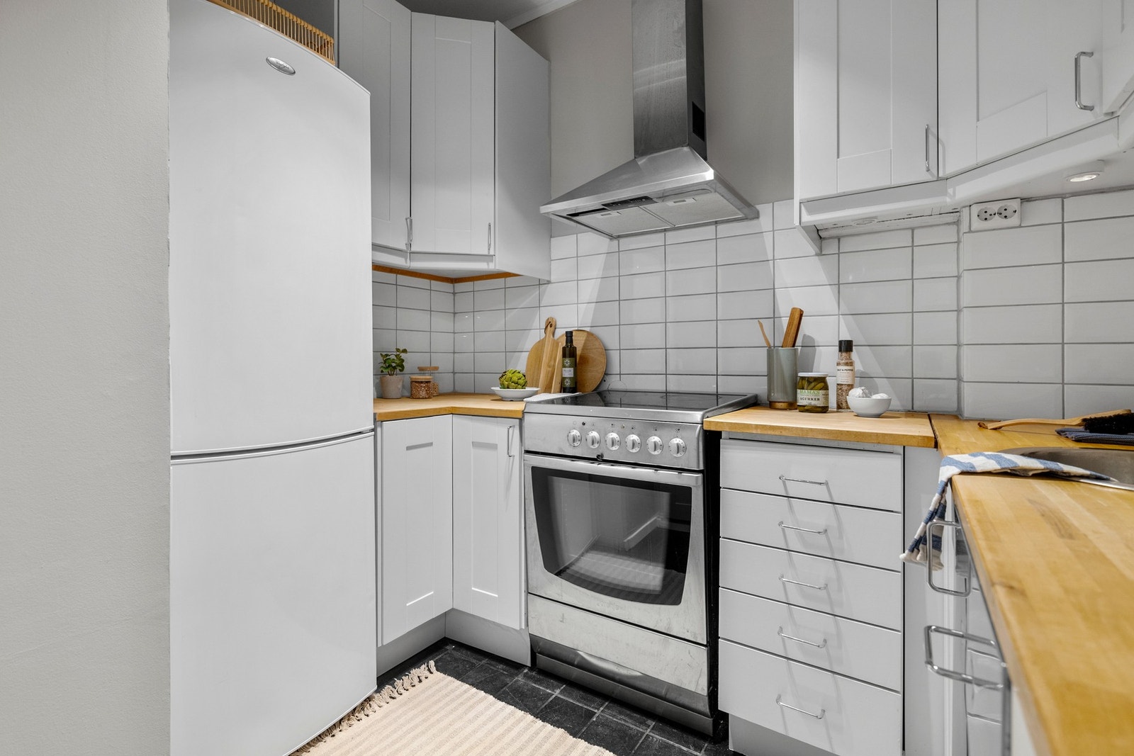 Innredningen har lyse profilerte fronter og benkeplate av tre med nedfelt oppvaskkum. På kjøkkenet er det plass til frittstående hvitevarer som komfyr, oppvaskmaskin og kjøleskap med frysedel. Galleribilde