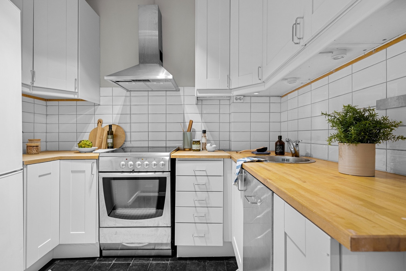 Leiligheten har et separat kjøkken med mørke fliser på gulv. Lys og tidløs kjøkkeninnredning med god skap- og benkeplass. Galleribilde