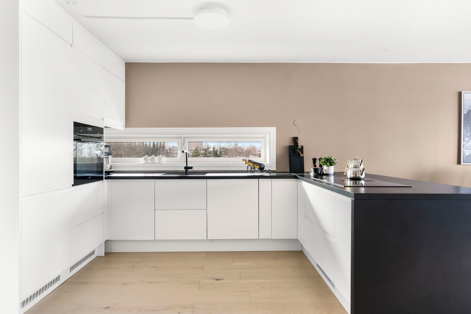 Veggflatene over benkeplaten er utført i glatt, malt overflate, noe som gir et helhetlig og lettstelt kjøkkenmiljø. Galleribilde