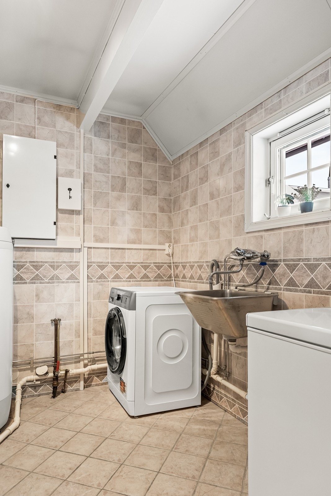 Separat teknisk rom/vaskerom, oppusset i 2011, med flislagt gulv og opplegg for vaskemaskin. Galleribilde