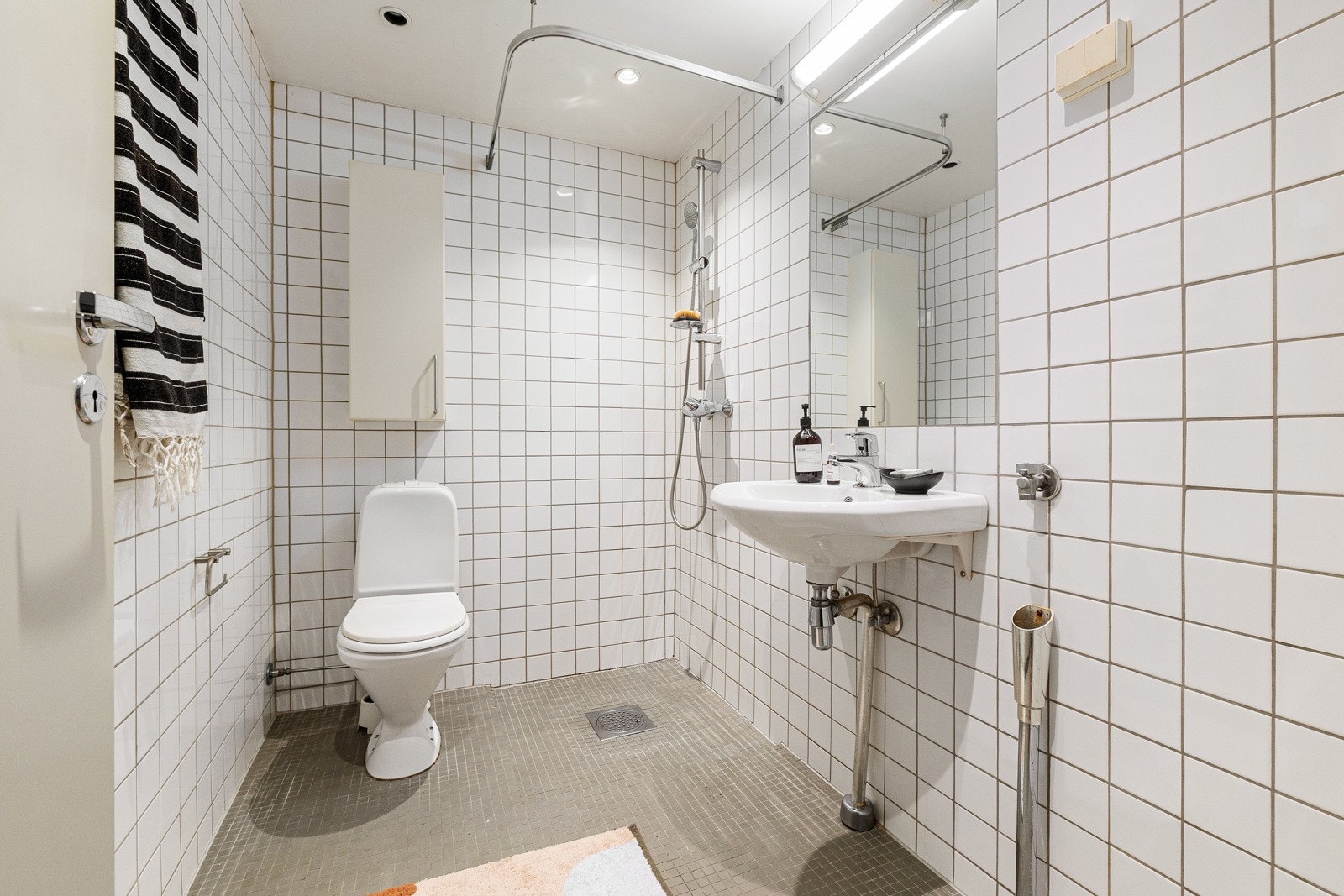 Badet er utstyrt med mekanisk avtrekk, opplegg for vaskemaskin, wc og dusjhjørne med ettgreps dusjbatteri, og hvit keramisk servant med ettgreps blandebatteri Galleribilde