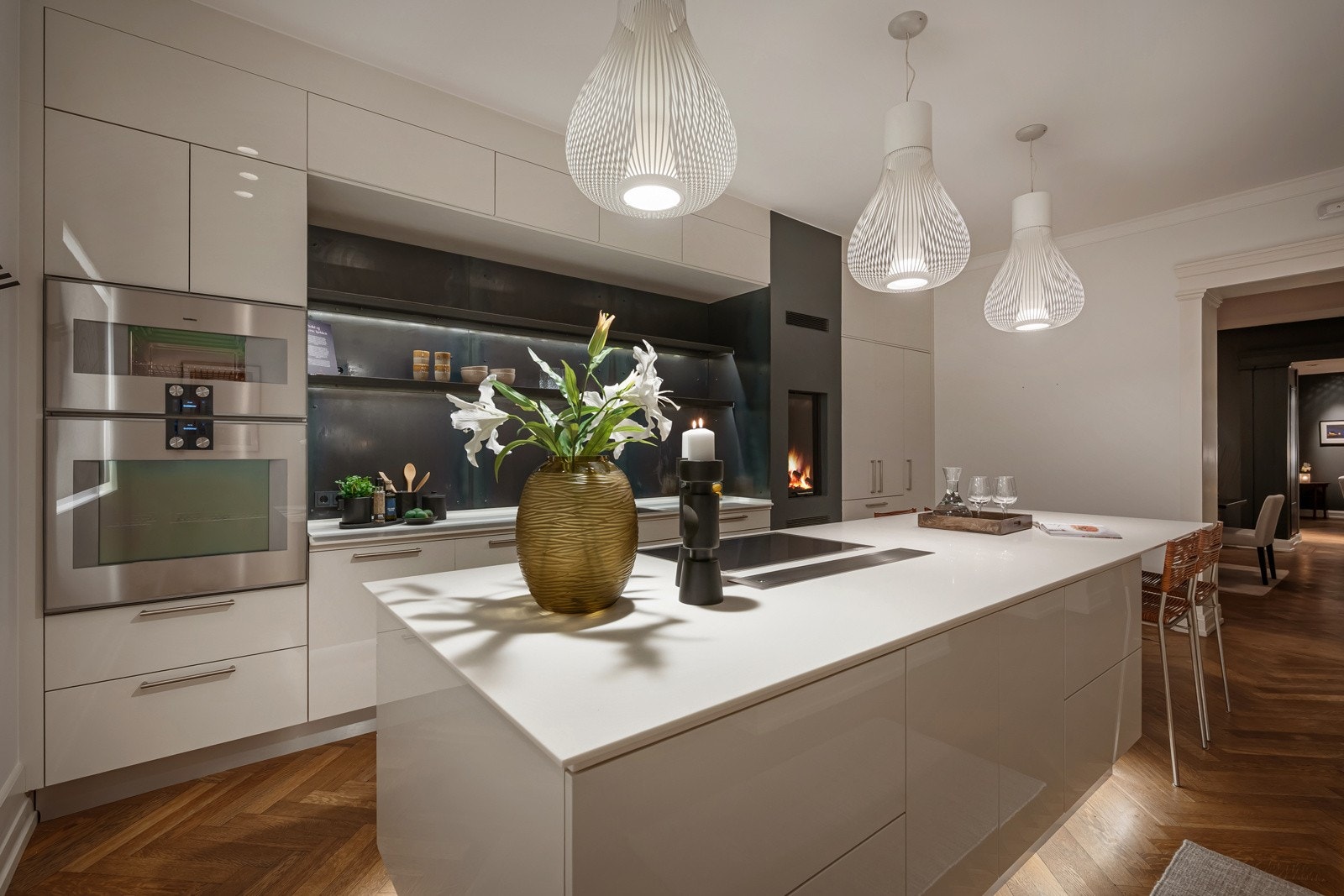 Stilrent design fra HTH som fremstår nærmest skreddersydd med innfelte, takhøye skap langs endeveggen rundt ildstedet, pluss en stor kjøkkenøy ut i rommet. Galleribilde