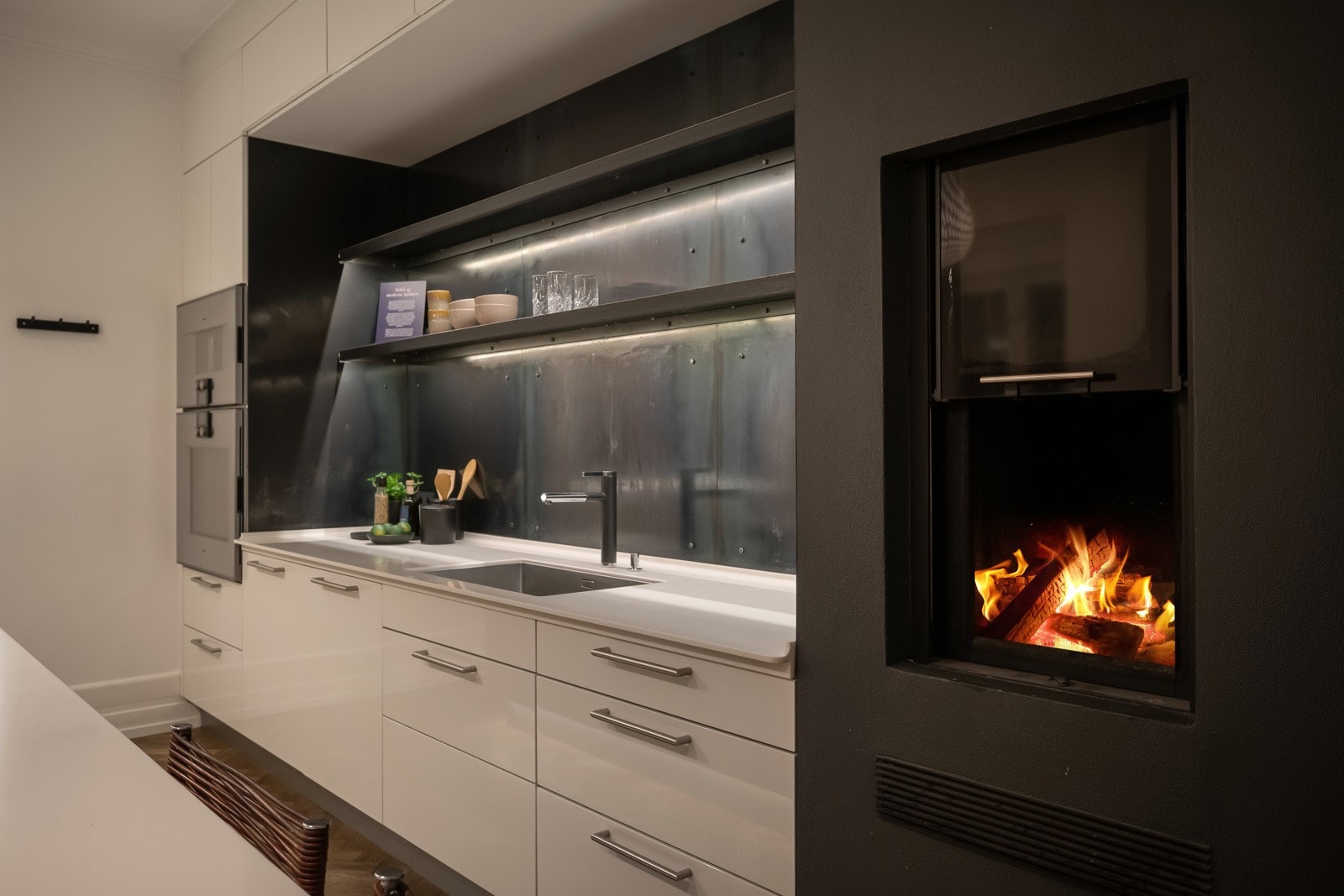 Innredningen har hvite, glatte høyglansfronter, kombinert med tynne, hvite benkeplater i Corian og kjøkkenet er utstyrt med kvalitetshvitevarer fra Gaggenau. Galleribilde