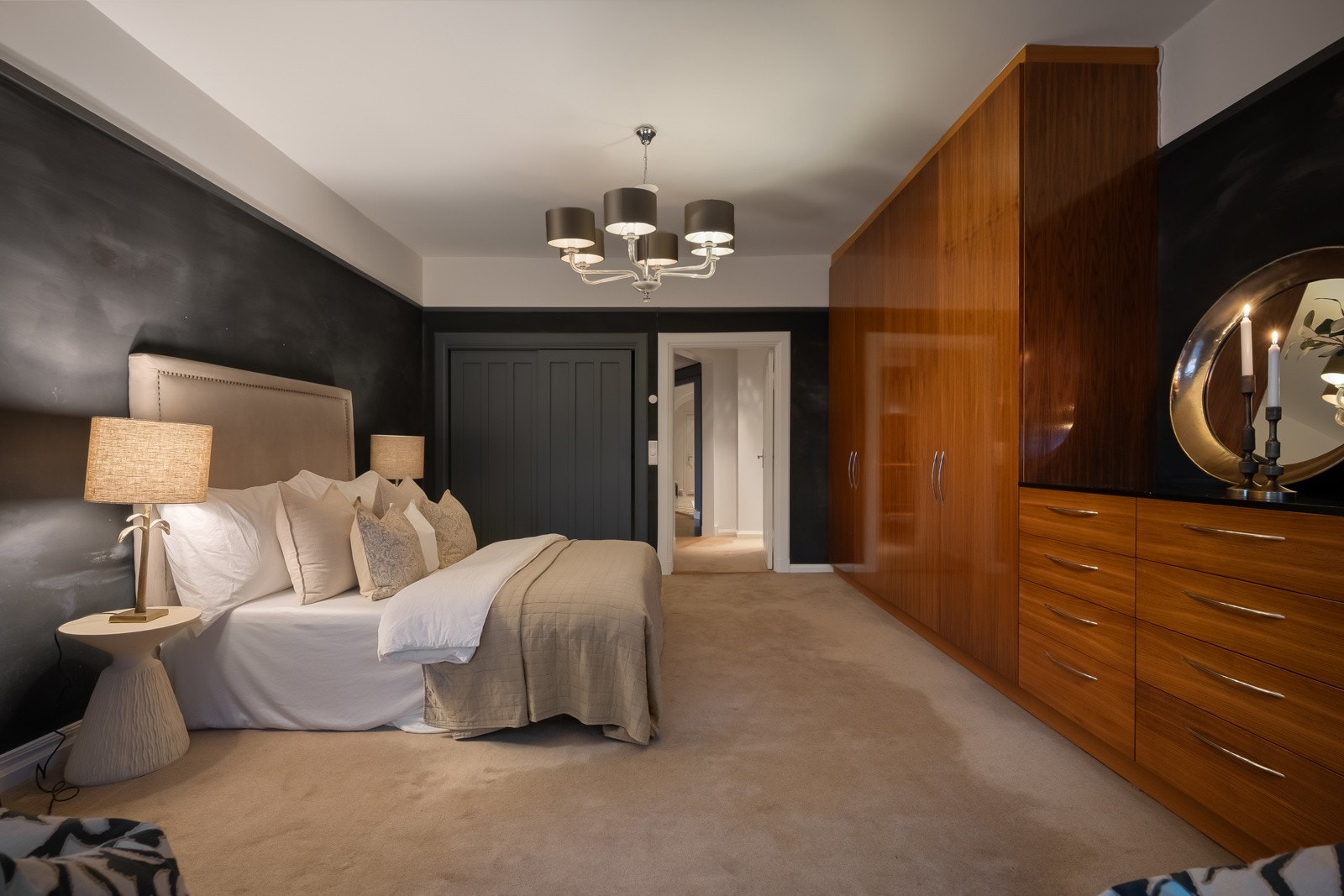 Innfelt i den ene veggen er det plassbygd skyvedørsgarderobe med mørke fronter, og langs langveggen er det montert en takhøy, spesialtilpasset garderoberekke og kommoder med glatte fronter i lakket eik. Galleribilde