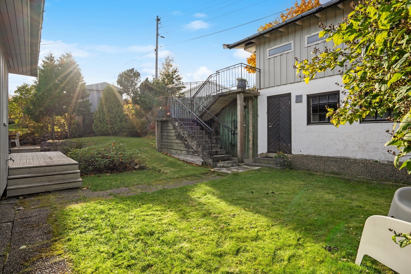 Beplantning av prydbusker, gressplen og hekk som rammer inn eiendommen. Galleribilde