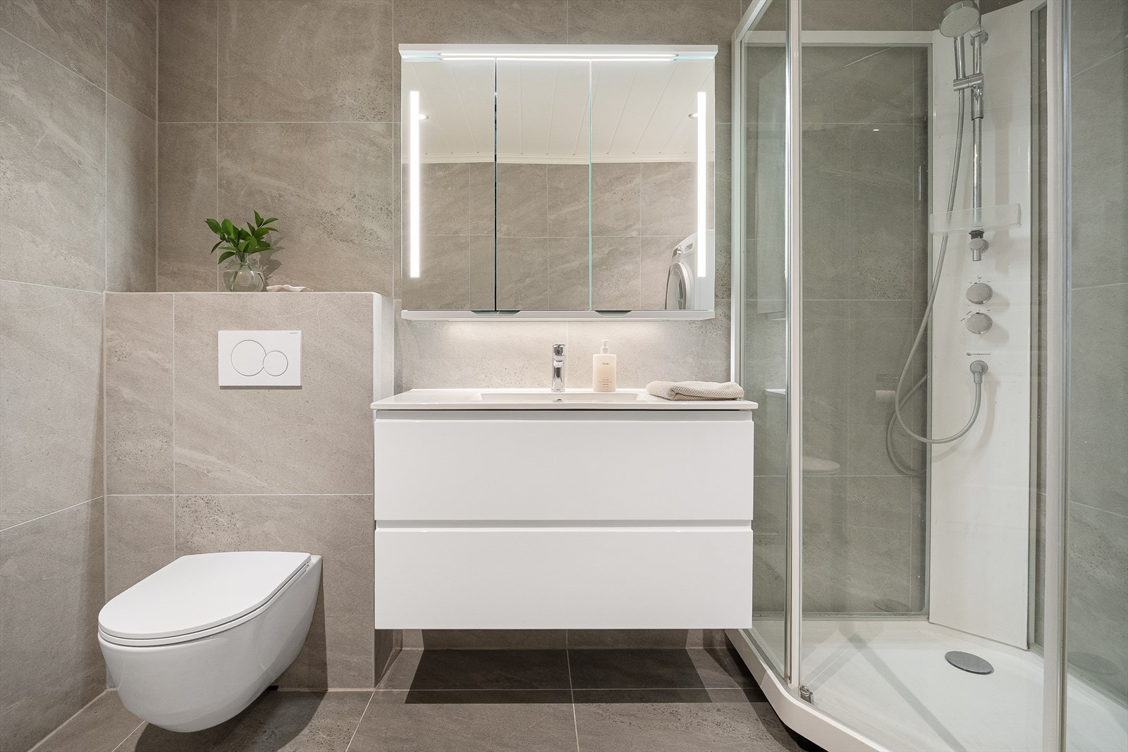 Her er det vegghengt toalett, dusj, servant med underskap og opplegg for vaskemaskin. Galleribilde