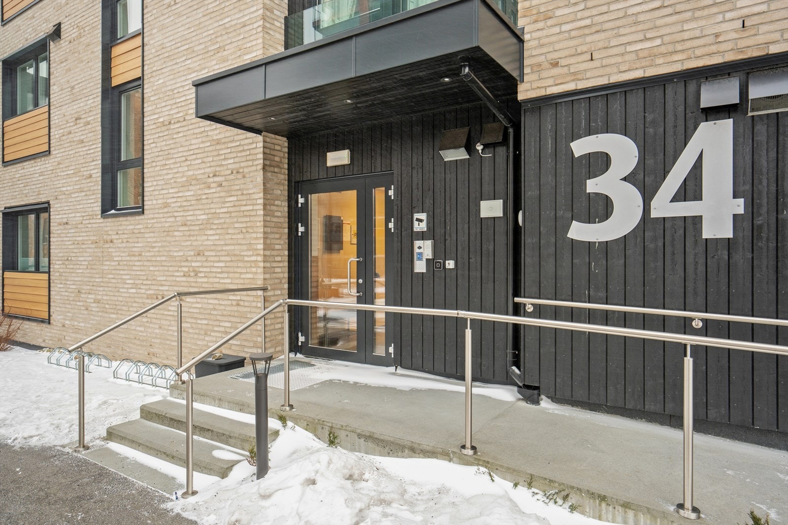 Leiligheten ligger i et moderne bygg fra 2022 med felles inngangsparti, dørcalling og kamera for trygg adkomst Galleribilde