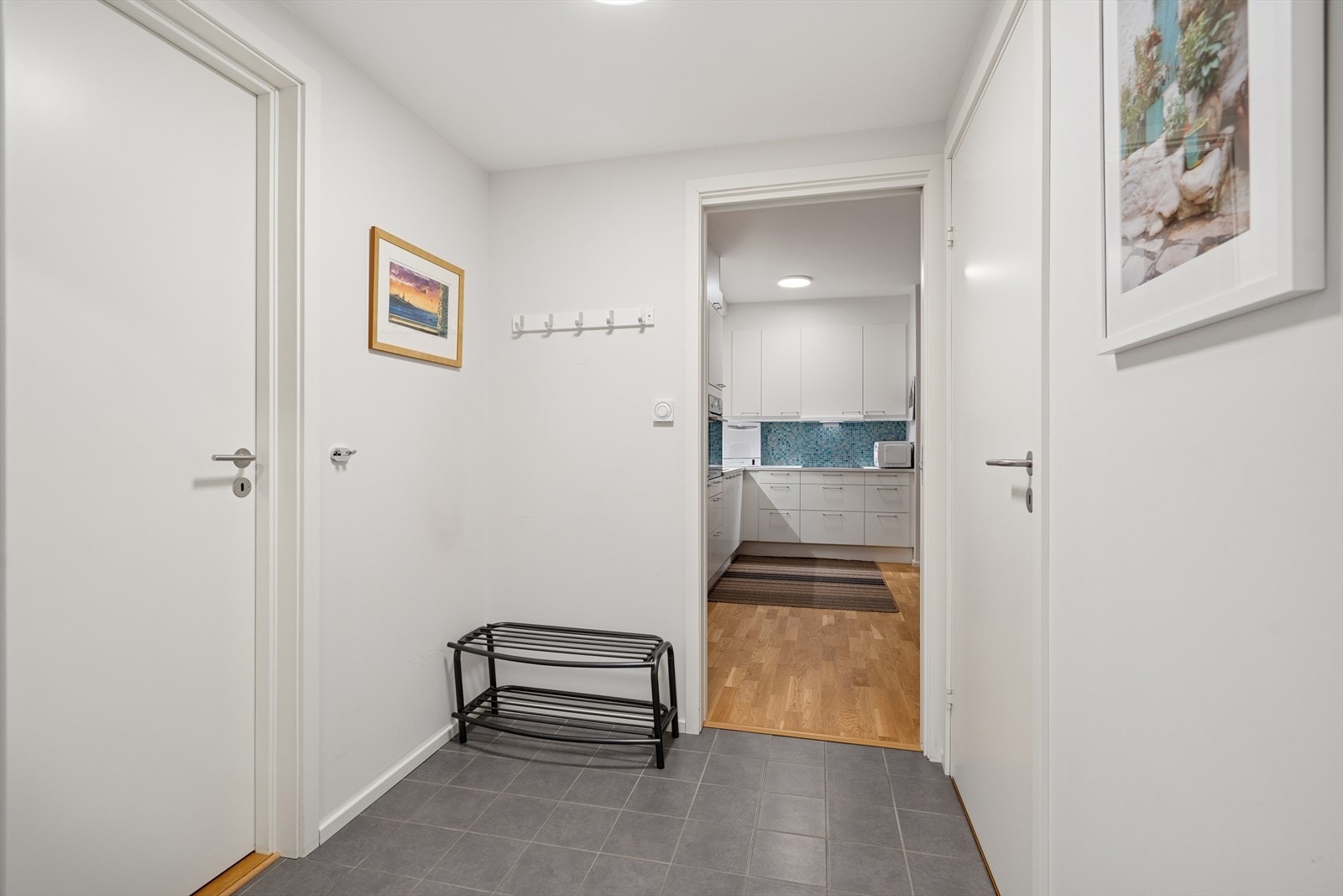 Gulvet i gangen er belagt med praktiske fliser, og de lyse, delikate veggene skaper en helhetlig og moderne stil som går igjen i hele leiligheten Galleribilde