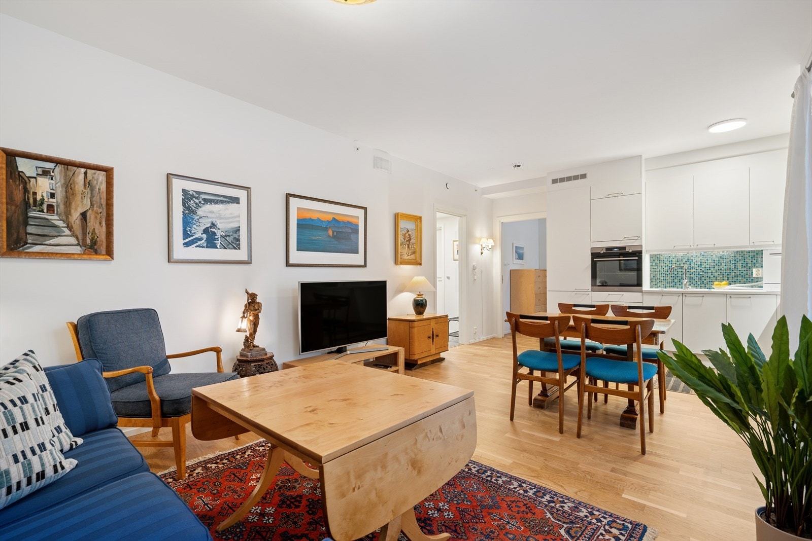 Vel inne i leiligheten møtes du av en åpen løsning mellom stue og kjøkken, noe som skaper et lyst, moderne og luftig oppholdsrom Galleribilde