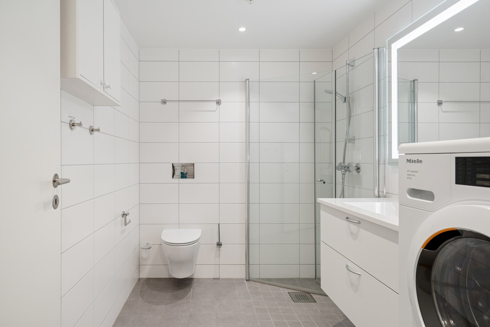 Baderomsinnredningen inkluderer en moderne servantseksjon med glatte fronter og en praktisk skuffeløsning som gir god oppbevaringsplass Galleribilde