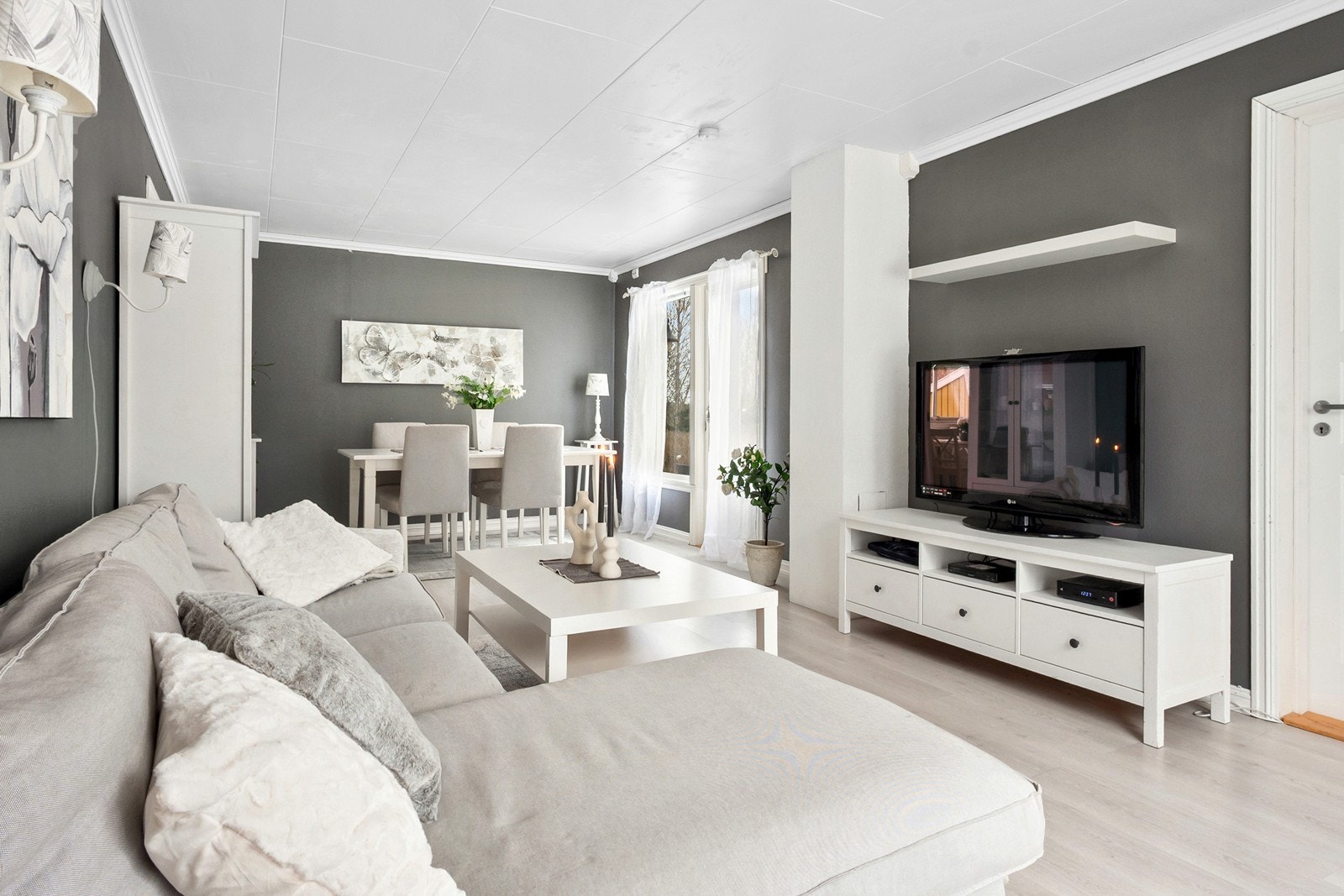 Stuen er malt i en moderne og lun gråtone, og har en naturlig og harmonisk inndeling med soner for både sofagruppe og spisestue. Galleribilde