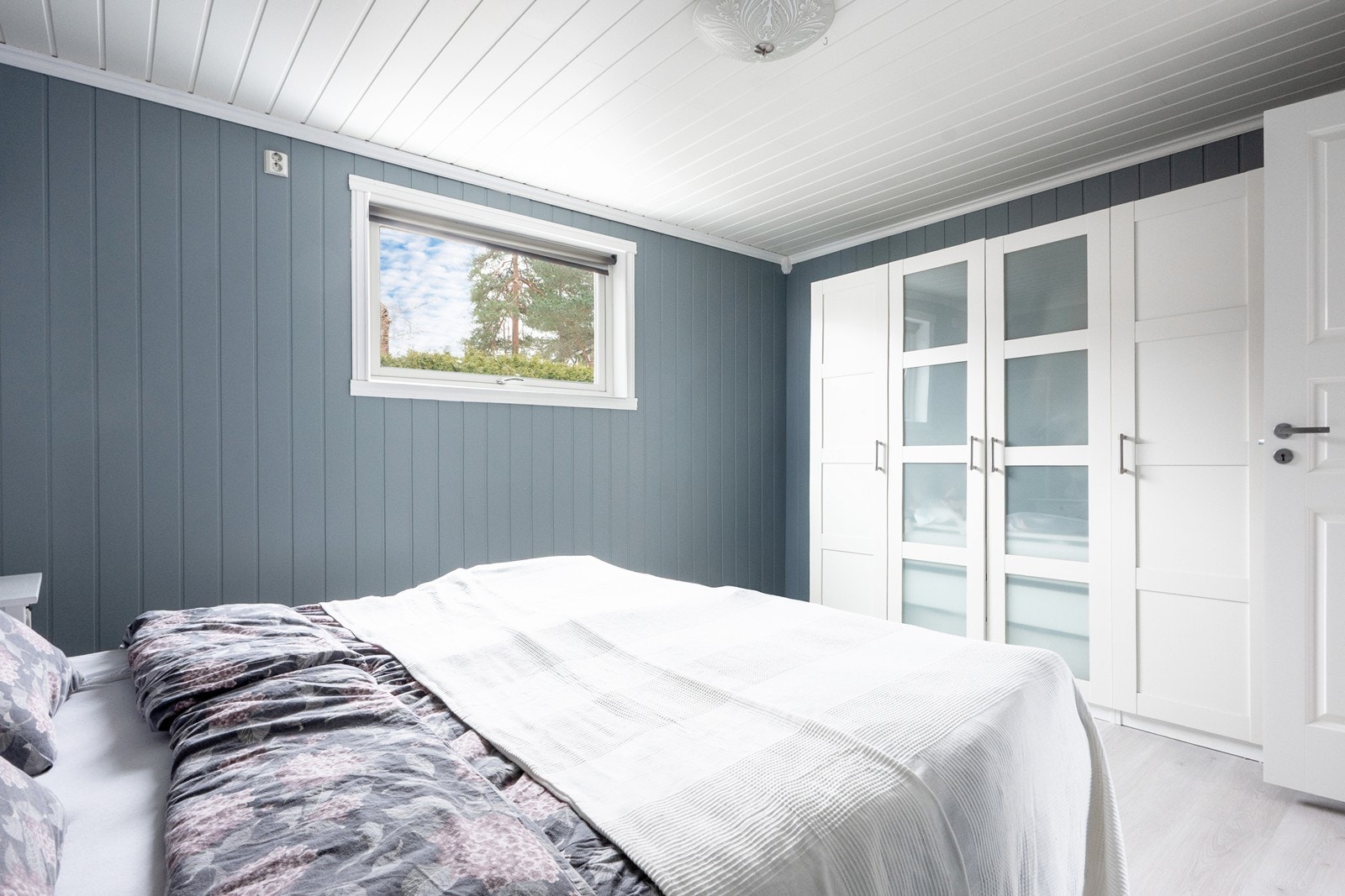 Rommet er romslig og malt i en behagelig blåfarge, med god plass til dobbeltseng og rikelig med skapplass langs den ene veggen. I tillegg er det gulvvarme som sørger for ekstra komfort. Galleribilde