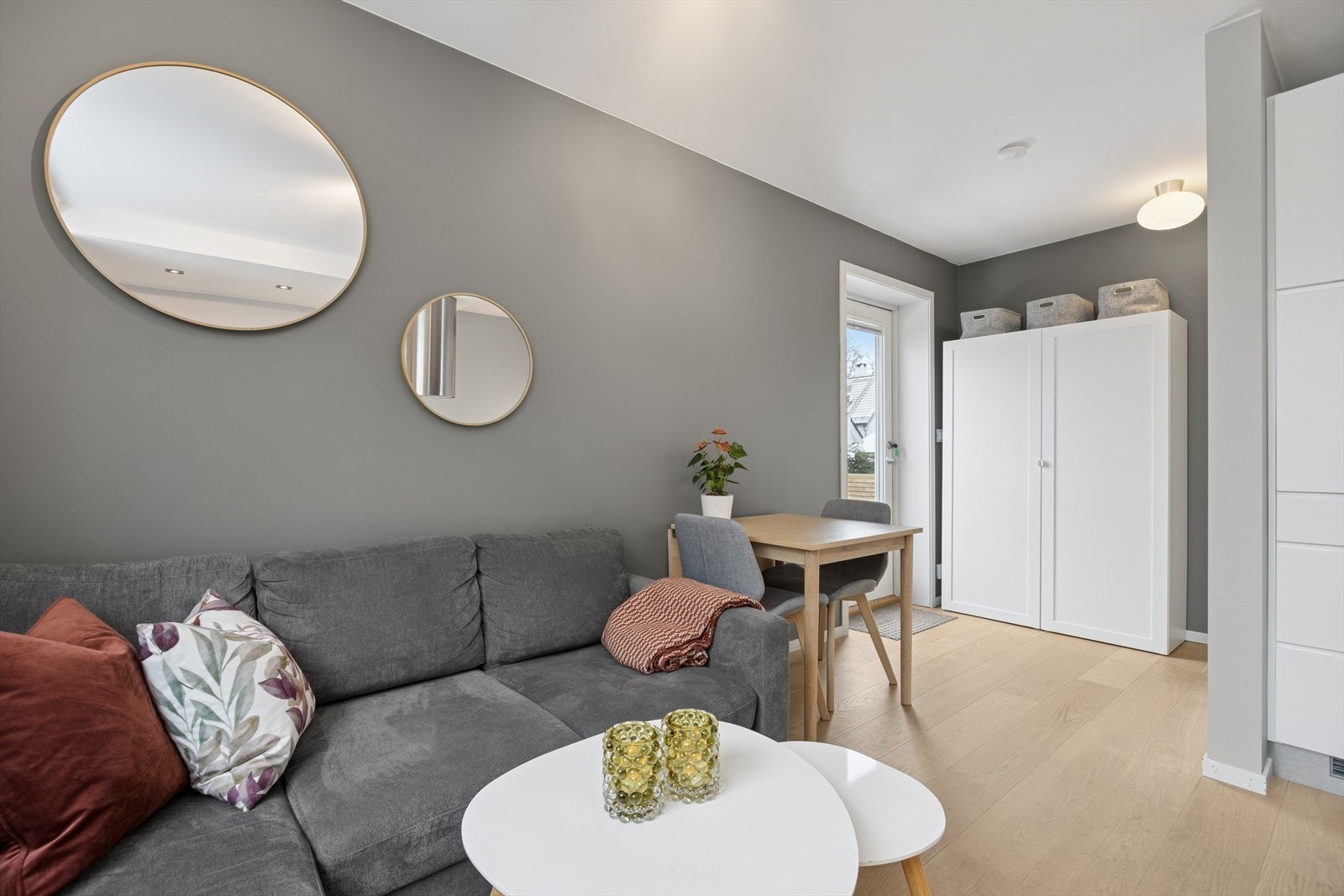 Pene overflater malt i tidsriktige farger gir et moderne preg på leiligheten. Inngangsdør med glassvindu bidrar til lysinnslipp. Det er også plissegardin til inngangsdøren. Galleribilde