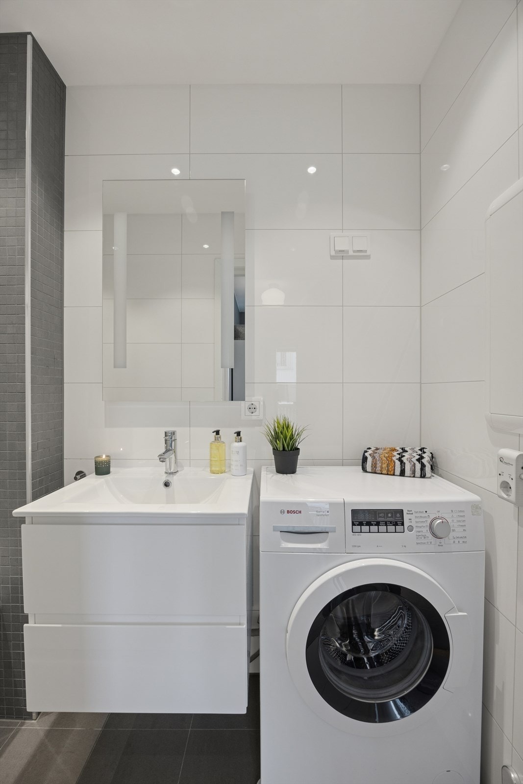 Her er det servant med praktisk underskap og speil med integrert belysning. Opplegg for vaskemaskin. Galleribilde