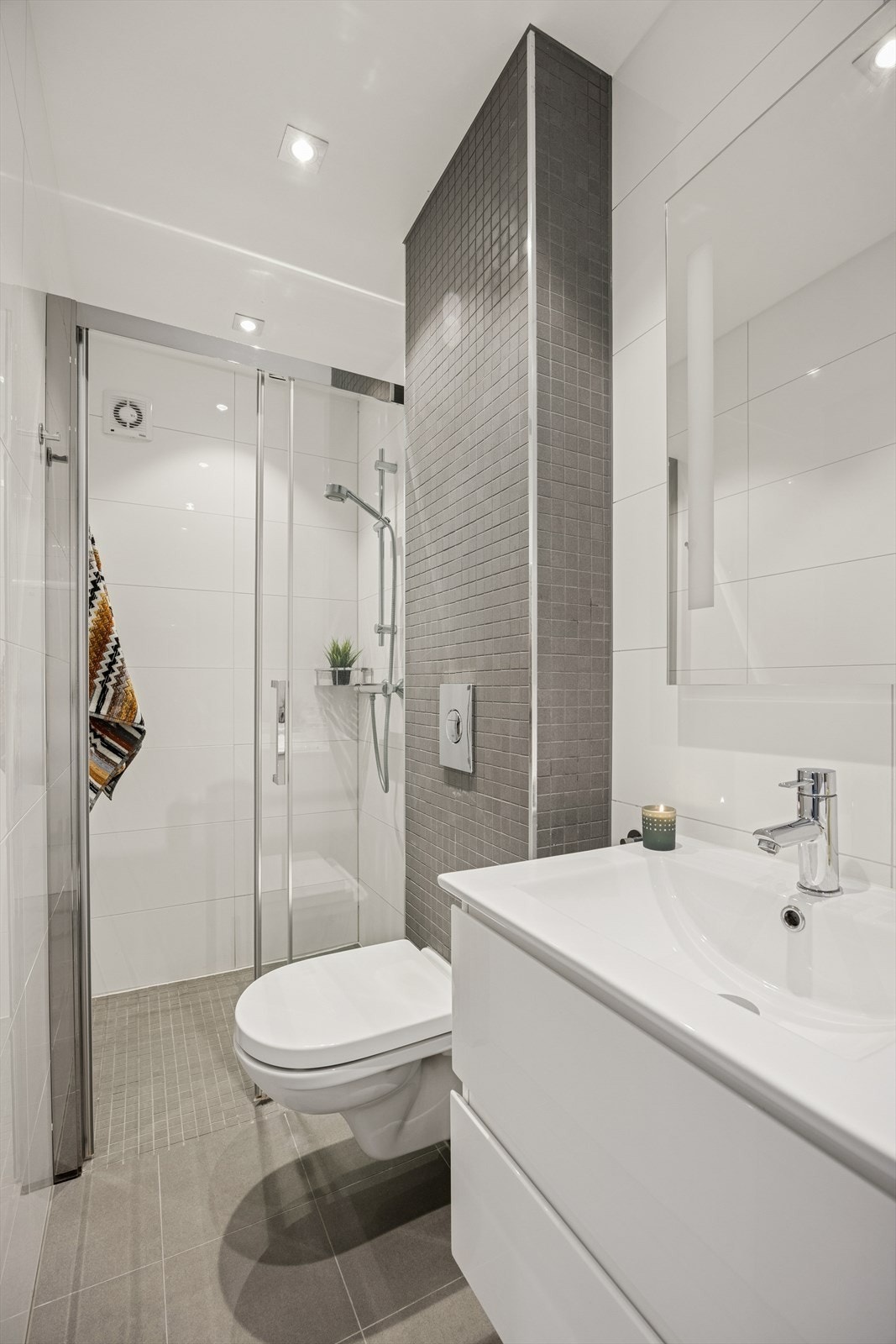 Lyst og delikat baderom med fliser på vegg og gulv. Elektriske varmekabler på gulvet.
Det er rom for å sette eks tørkestativ i dusjen for å tørke klær. Galleribilde