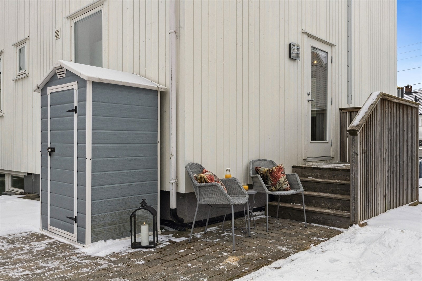 Koselig og skjermet inngangsparti med en solrik hellelagt uteplass. Utvendig bod tilhører leiligheten. Galleribilde