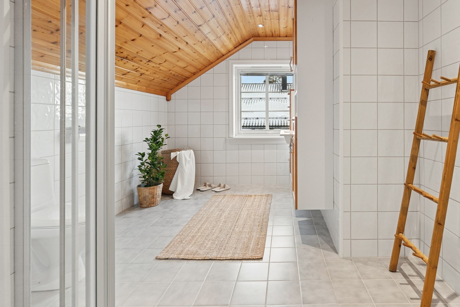 Lyst og pent baderom i andre etasje har flislagte overflater og panel i taket. Galleribilde