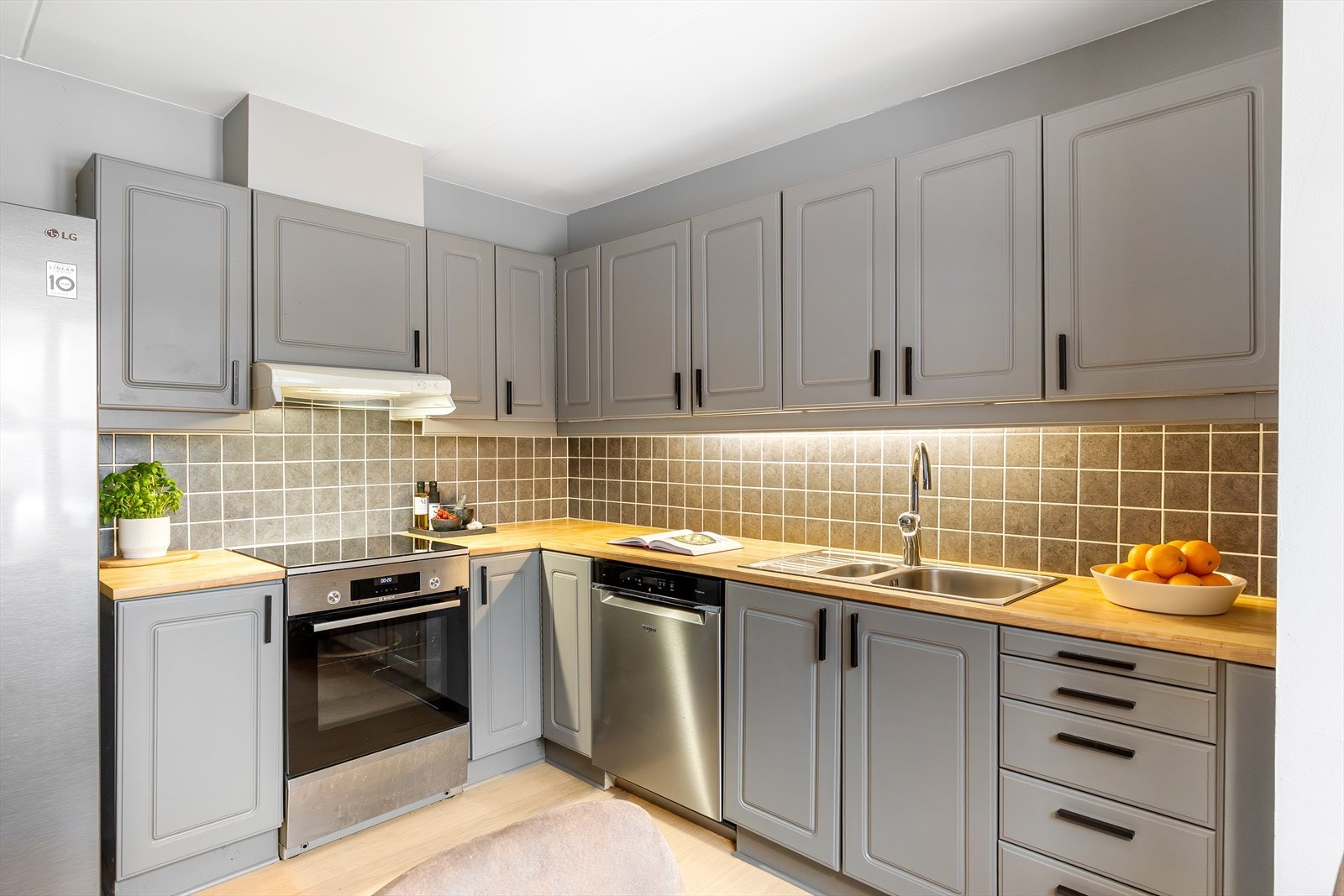 Det er flislagt mellom benkeskap og overskap, med integrert lys/lyslist under overskapene. Det er tilrettelagt med opplegg for oppvaskmaskin. Galleribilde