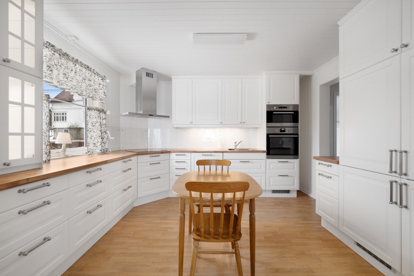 Koselig kjøkken med innredning med profilerte fronter og benkeplater av laminat med nedfelt oppvaskkum. Galleribilde