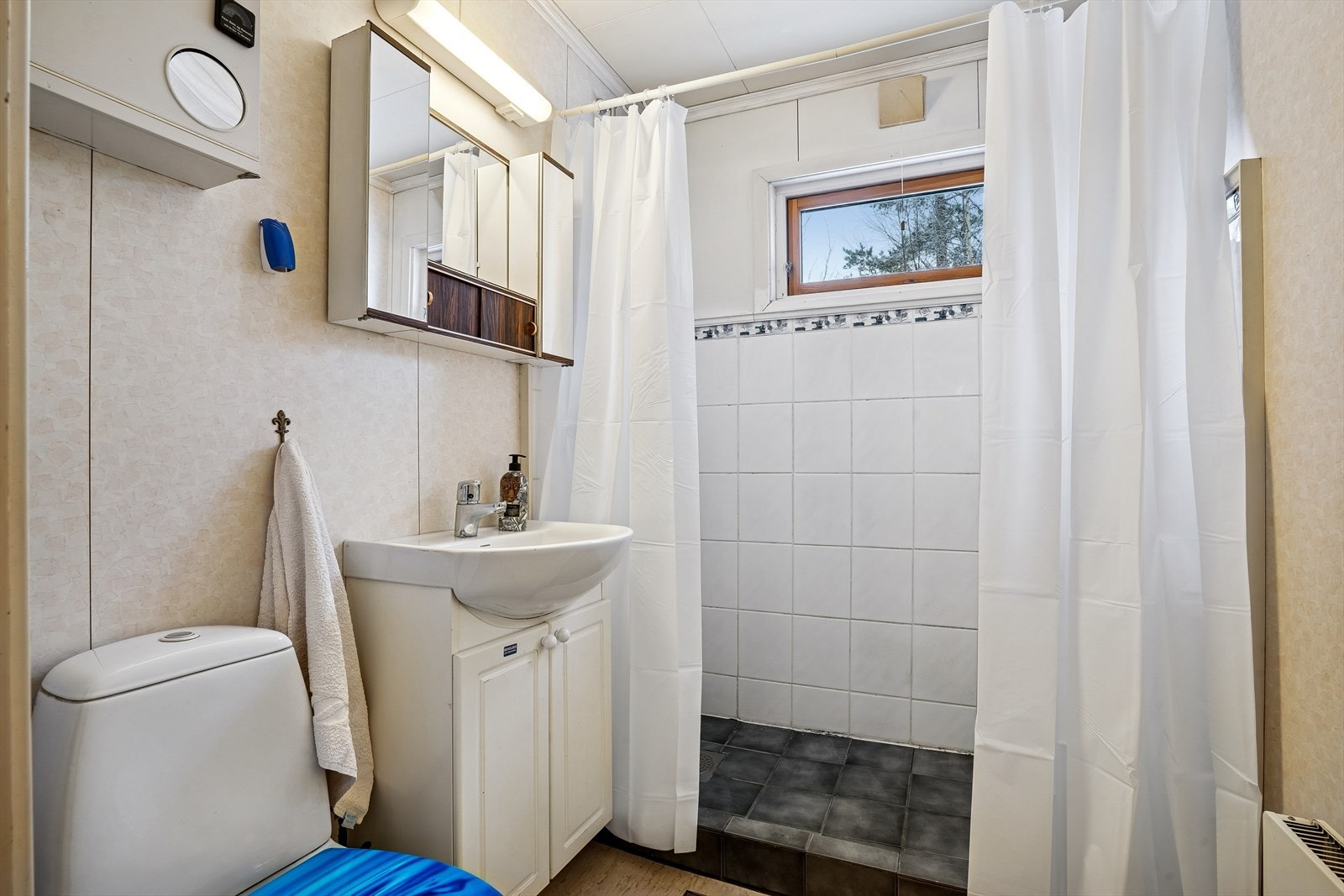 Badet er utstyrt med servant i innredning, gulvmontert WC og en dusjnisje. Galleribilde