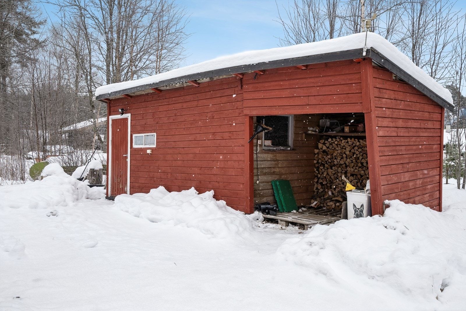 Frittstående uthus på ca. 10 m² med en tilhørende åpen vedbod på ca. 5 m². Galleribilde