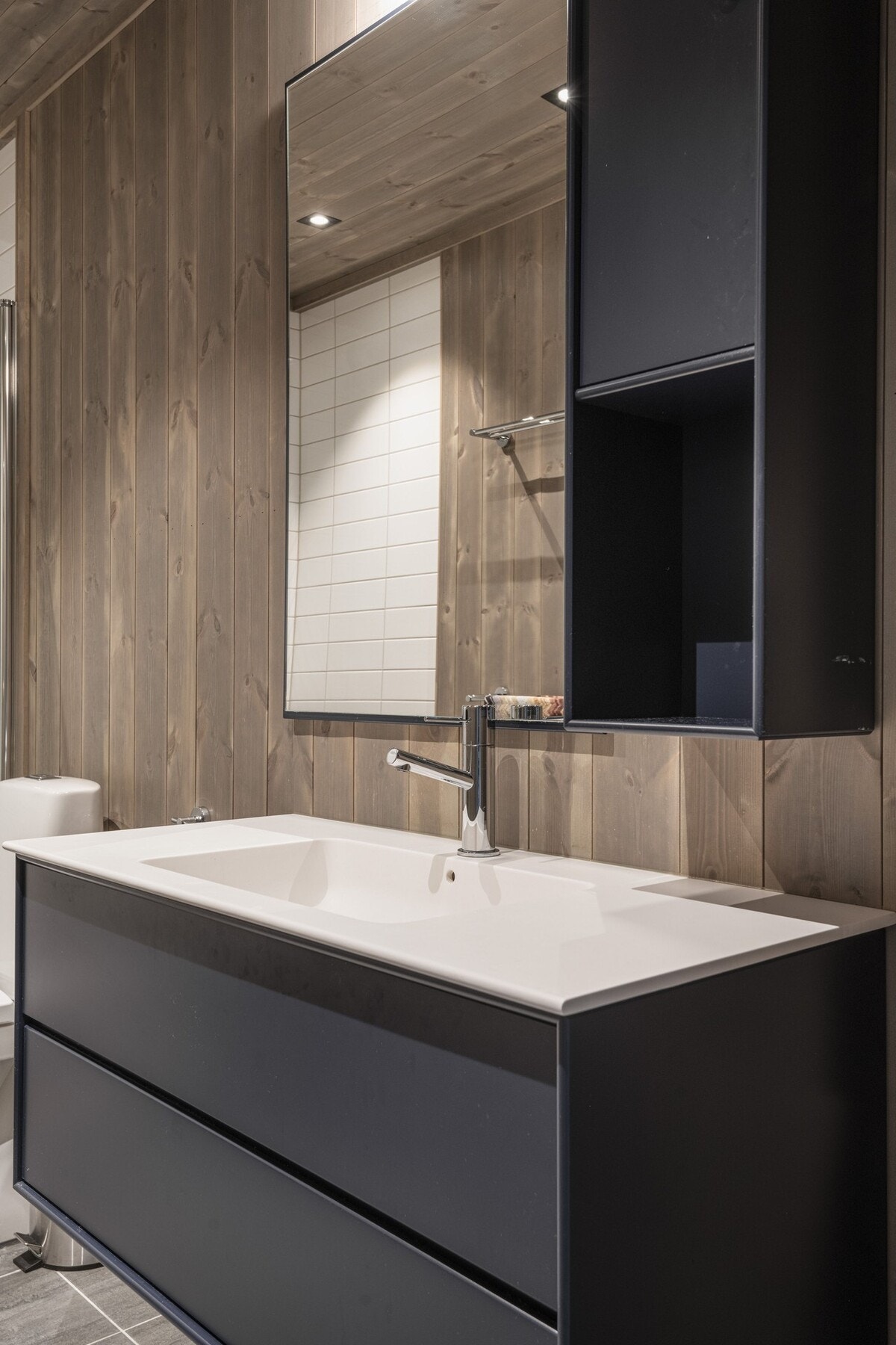 Badene har dusjhjørne med glassvegg, wc og servant med underskuffer. Galleribilde