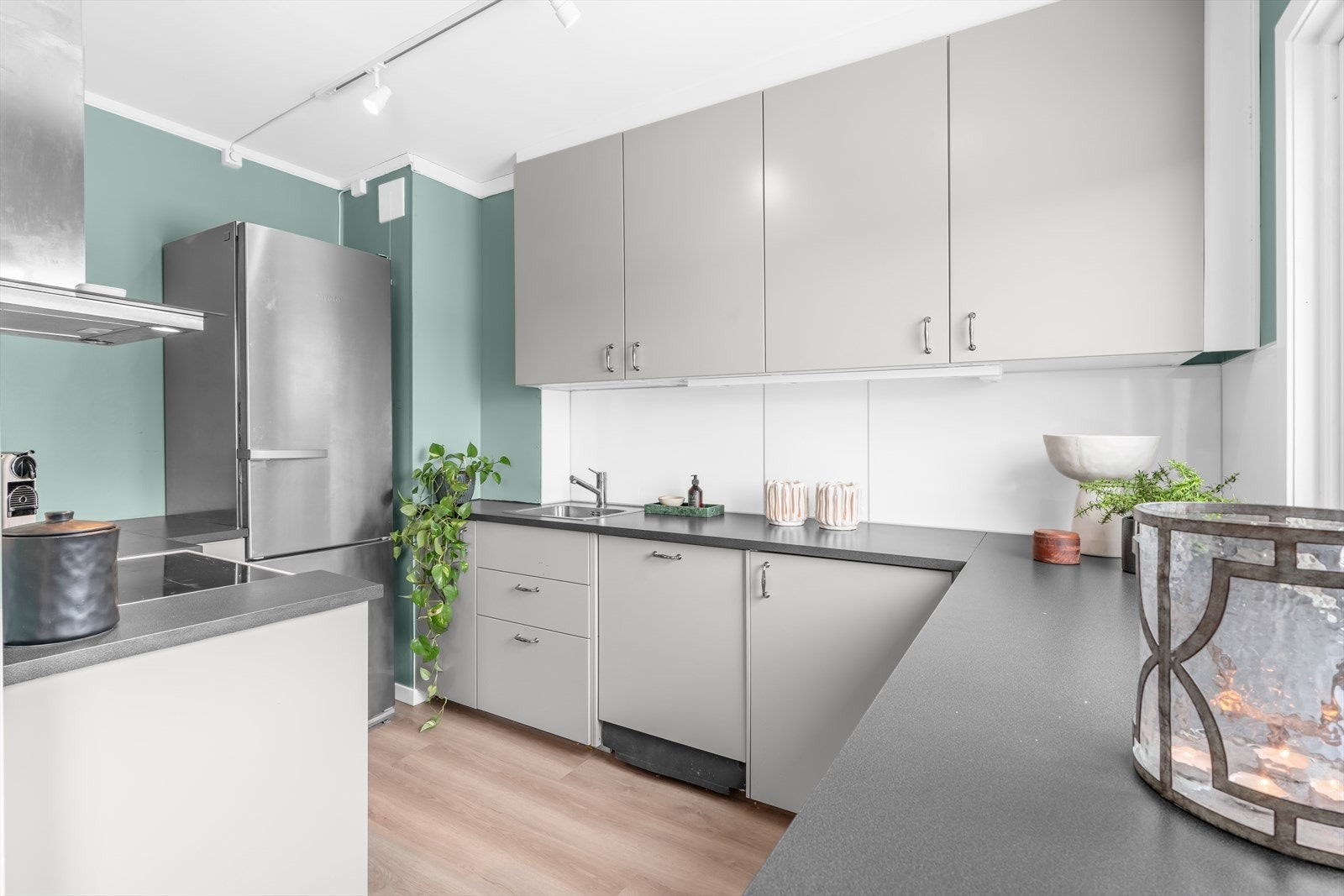 Kjøkkeninnredning med glatte fronter, laminatbenkeplate og en nedfelt kum i rustfritt stål. Galleribilde