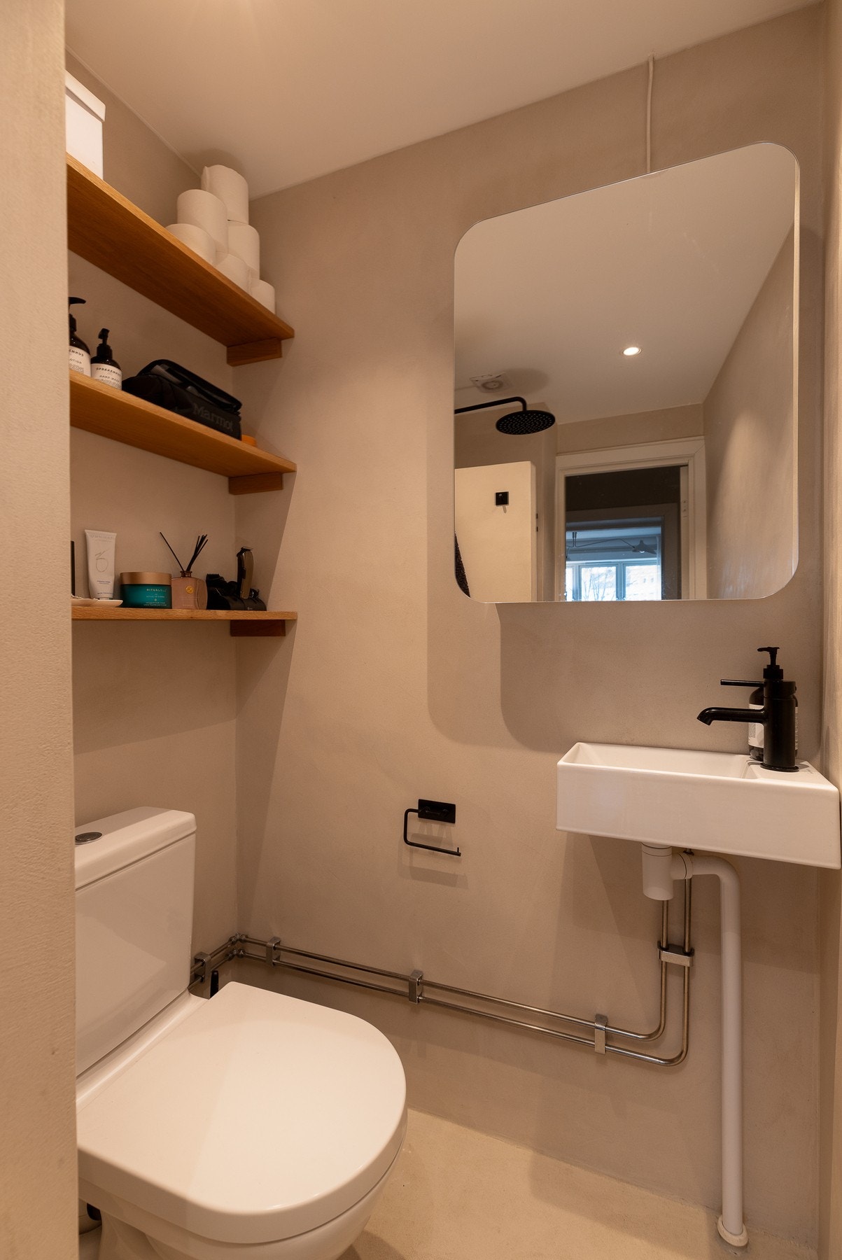 Badet har varmekabler, dusj med dusjvegg, servant, lekre trehyller til oppbevaring og WC. Galleribilde