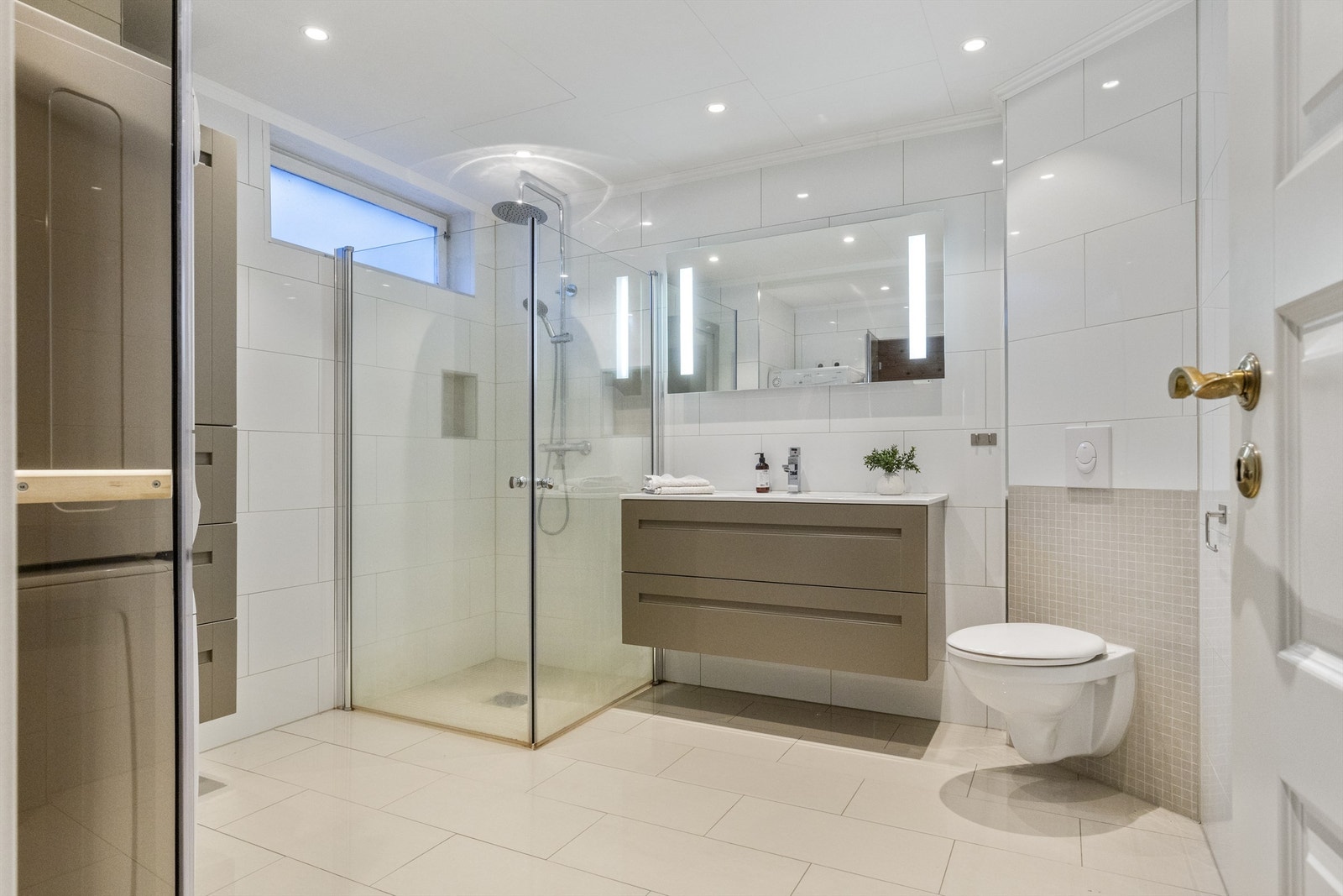 Romslig bad fra ca. 2018 med dusjhjørne som har foldedører av glass samt regnfallsdusj. Galleribilde