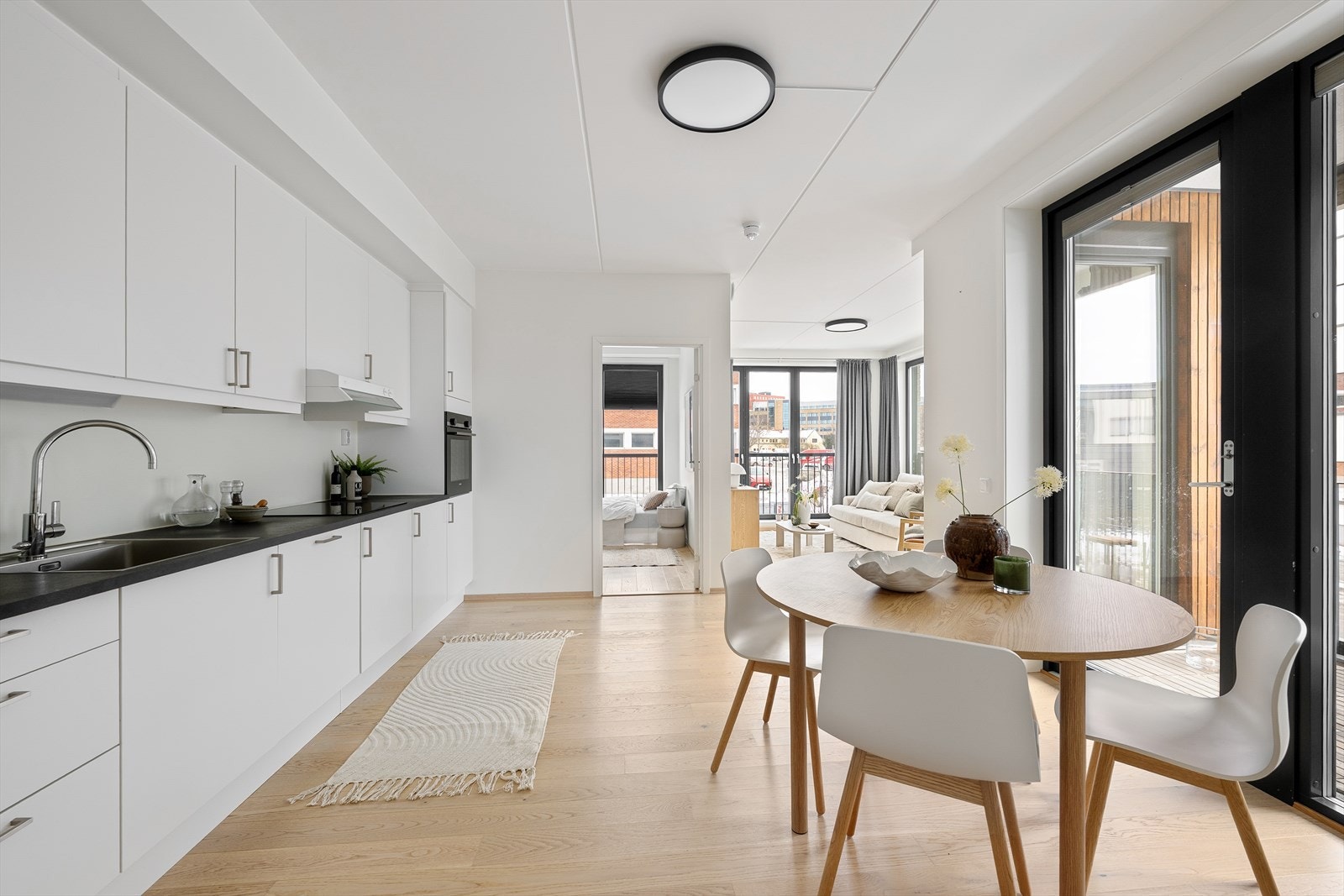 Kjøkkeninnredning med hvite glatte fronter og laminert benkeplate med nedfelt kum i rustfritt stål Galleribilde