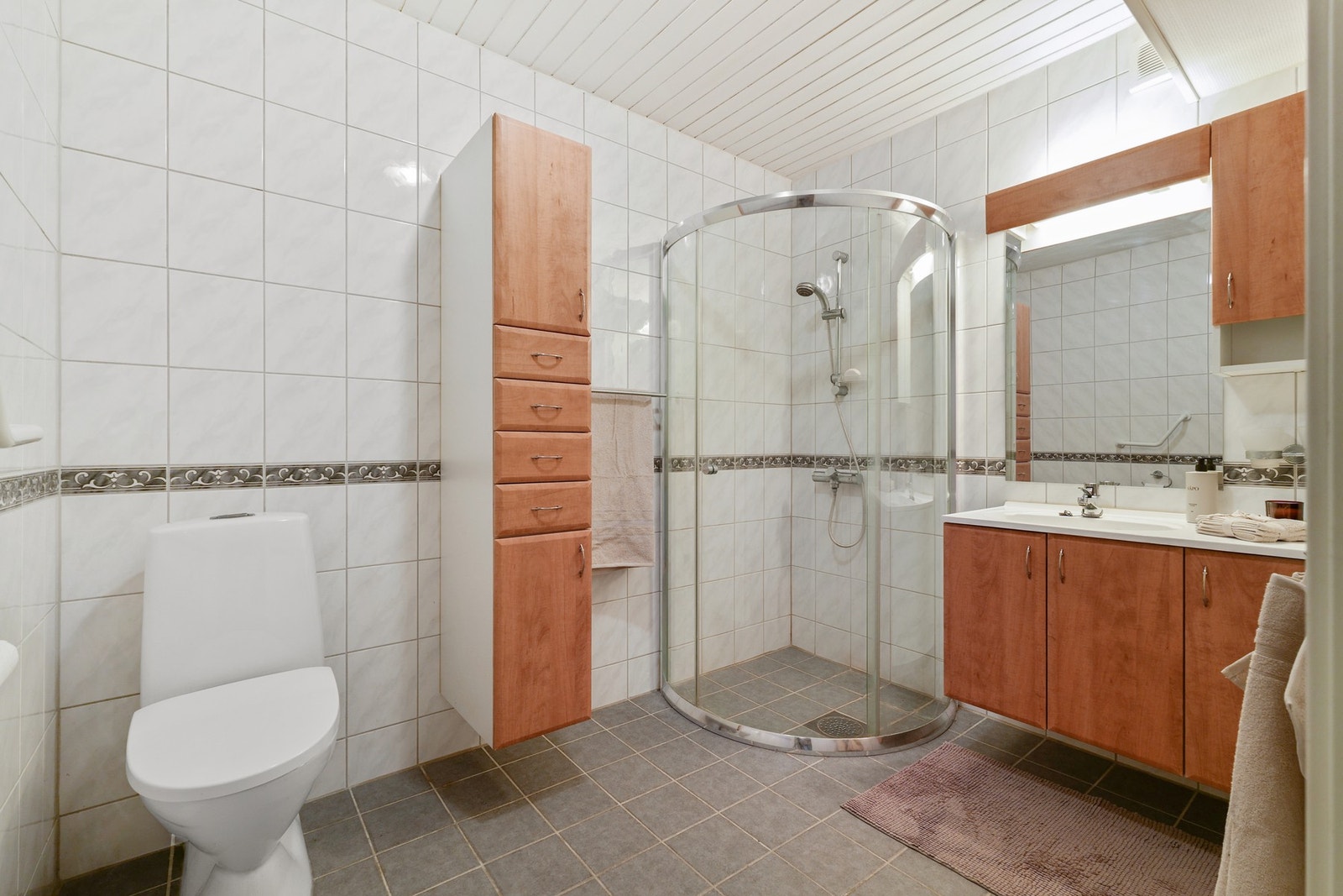 Badet er utstyrt med dusjhjørne, toalett og servant i skap. Galleribilde