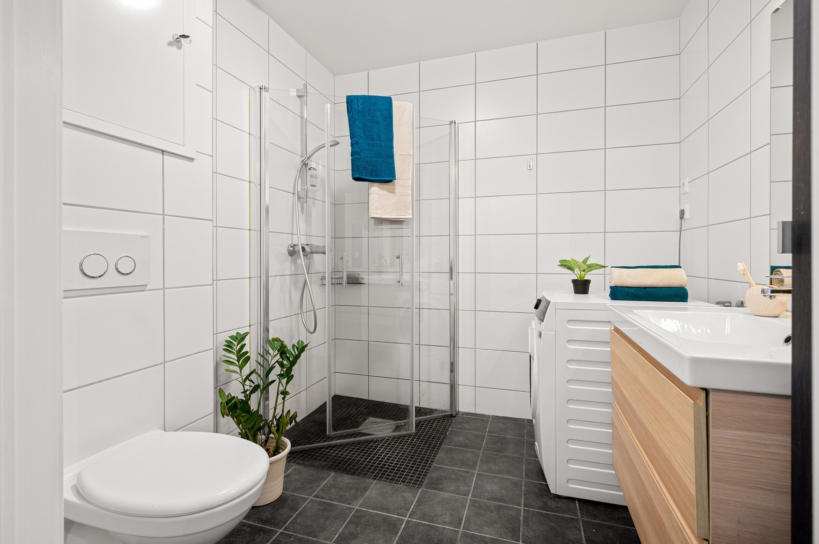 Badet er innredet med baderomsinnredning, servant, speil, overlys, veggmontert toalett og dusjhjørne. Galleribilde