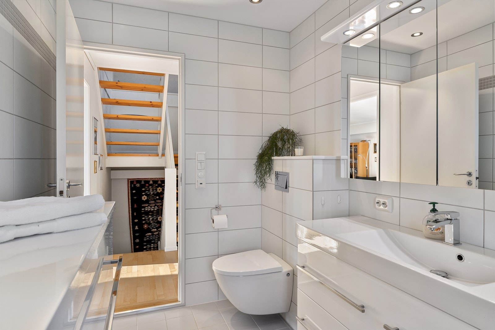 Pent helfliset bad med vegghengt wc, dusjhjørne, vask i seksjon og varme i gulv for ekstra komfort. Galleribilde