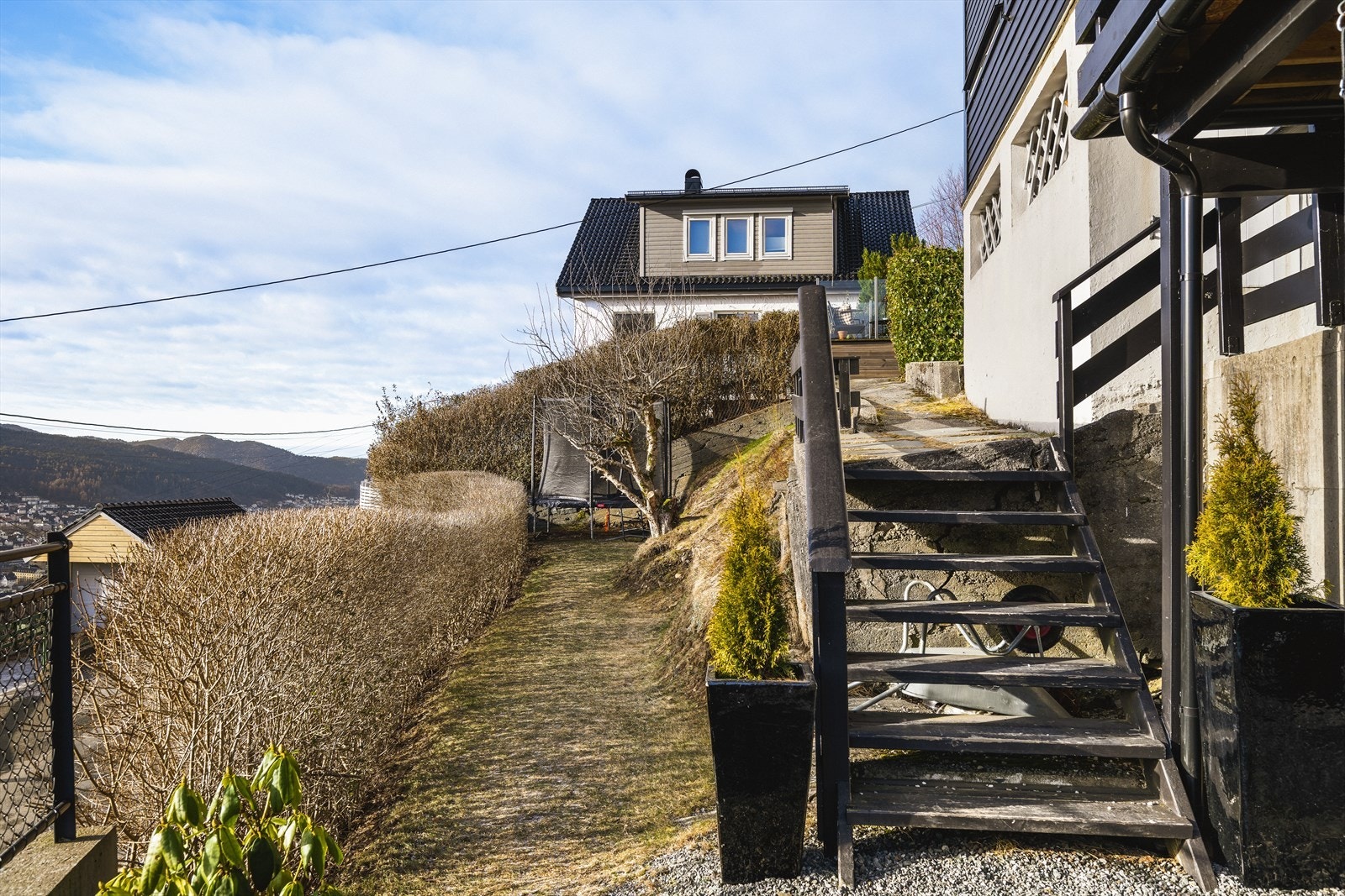 Fra carport til leiligheten passerer du en hyggelig hage som gir et grønt og trivelig preg på adkomsten. Galleribilde