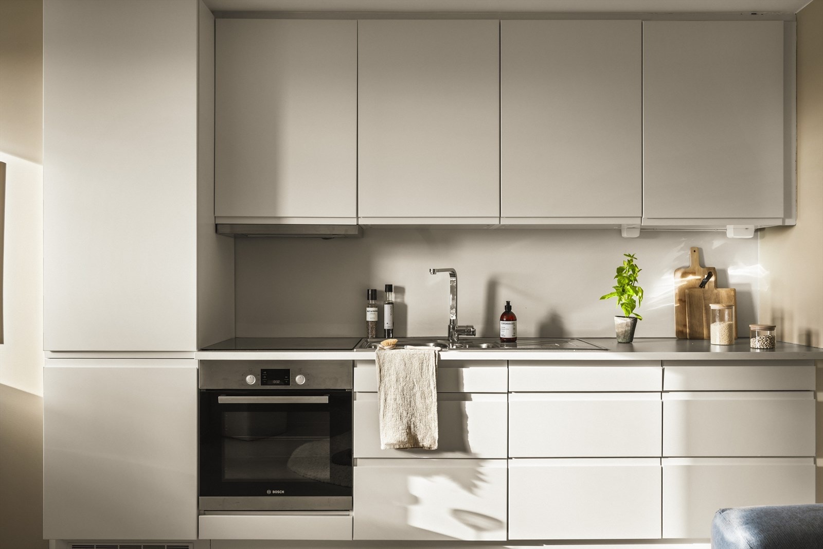 HTH-kjøkken med glatte fronter og integrert gripekant. Utstyrt med integrerte hvitevarer samt vannstoppsystem og komfyrvakt. Galleribilde