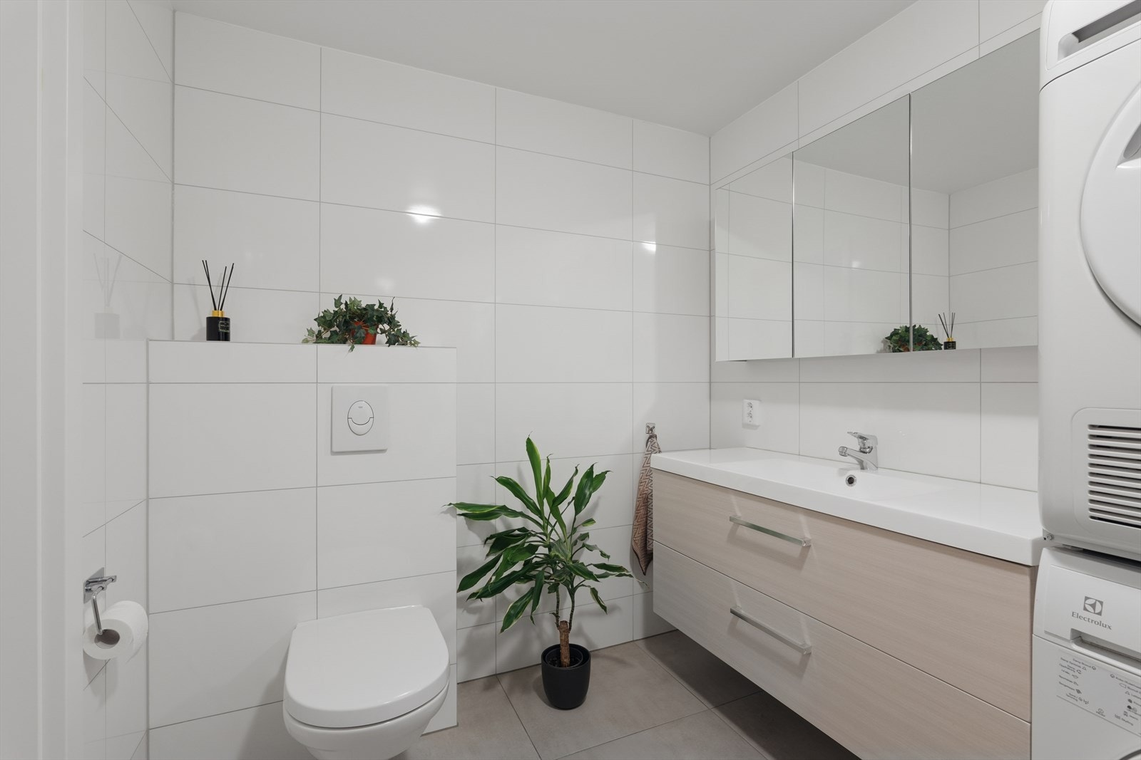 Badet er flislagt med vegghengt toalett og moderne skuffeløsning for diverse oppbevaring Galleribilde