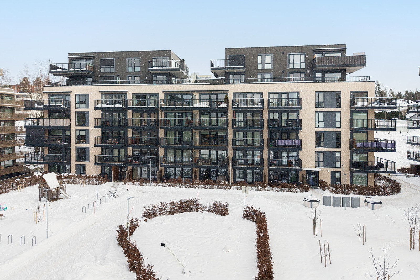 Under denne snøen er det lagt til rette for både lek, rekreasjon og rolige pauser i grønne omgivelser, og området fungerer som et naturlig samlingspunkt for beboerne. Galleribilde