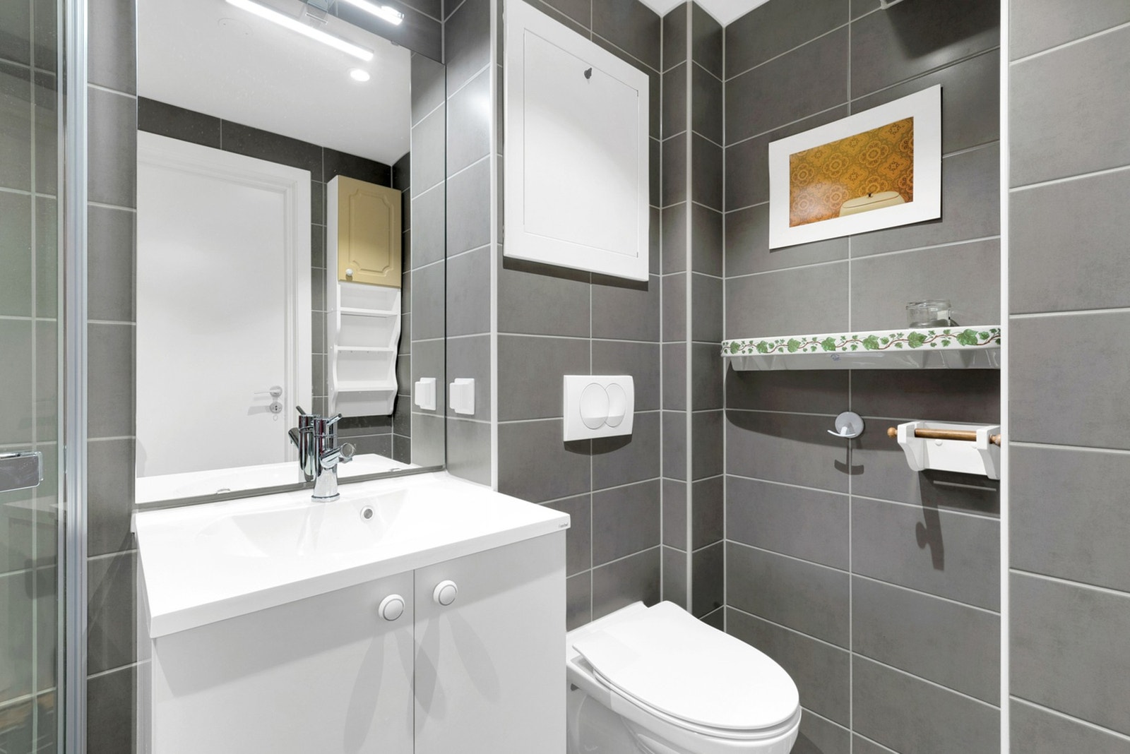 Innredningen består av dusjhjørne med glassdører, vegghengt toalett, nedsenket servant og speilskap. Galleribilde