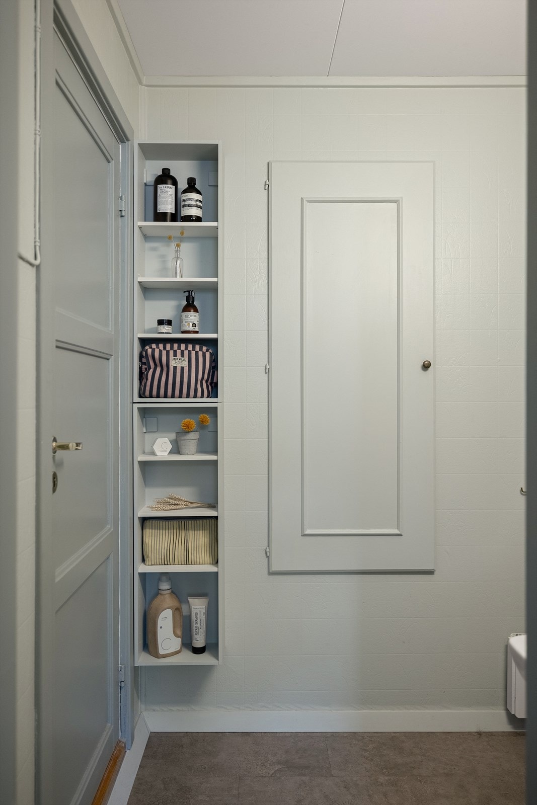 På badet er det laget en plassbygde hylle som gir smart og arealeffektiv oppbevaring på badet. I tillegg er den gamle døren til stuen omgjort til skap for ytterligere oppbevaring. Galleribilde