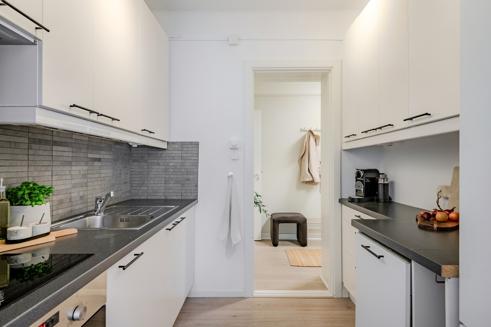 Lyst og innbydende kjøkken (2010) med glatte fronter, laminatbenkeplate og fliser mellom benk og overskap. Integrerte hvitevarer og godt arbeidslys gir en praktisk løsning, med direkte adkomst til soverommet. Galleribilde