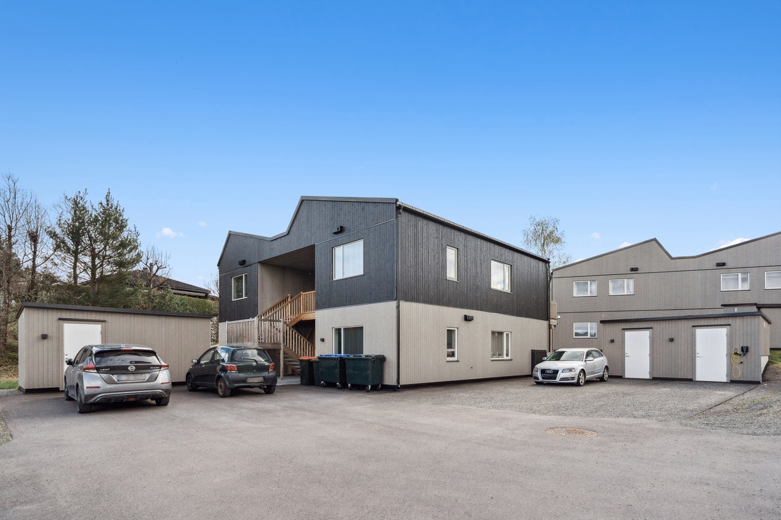 Stor felles gårdsplass med god plass for parkering av bil. Eier har disponert parkeringsareal foran utebod, hvor det er lagt opp elbillader på veggen. Galleribilde