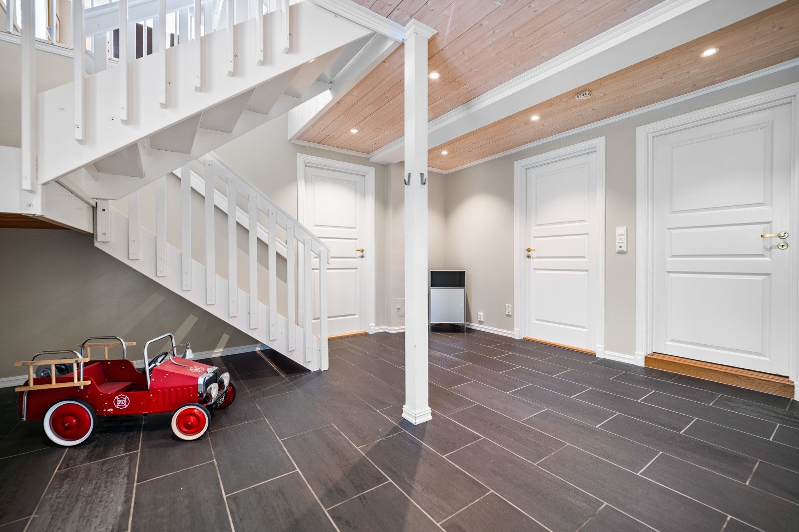 En hvitmalt trapp med åpne trinn fører videre opp til hovedplan med stue, kjøkken, vaskerom og toalettrom. Galleribilde