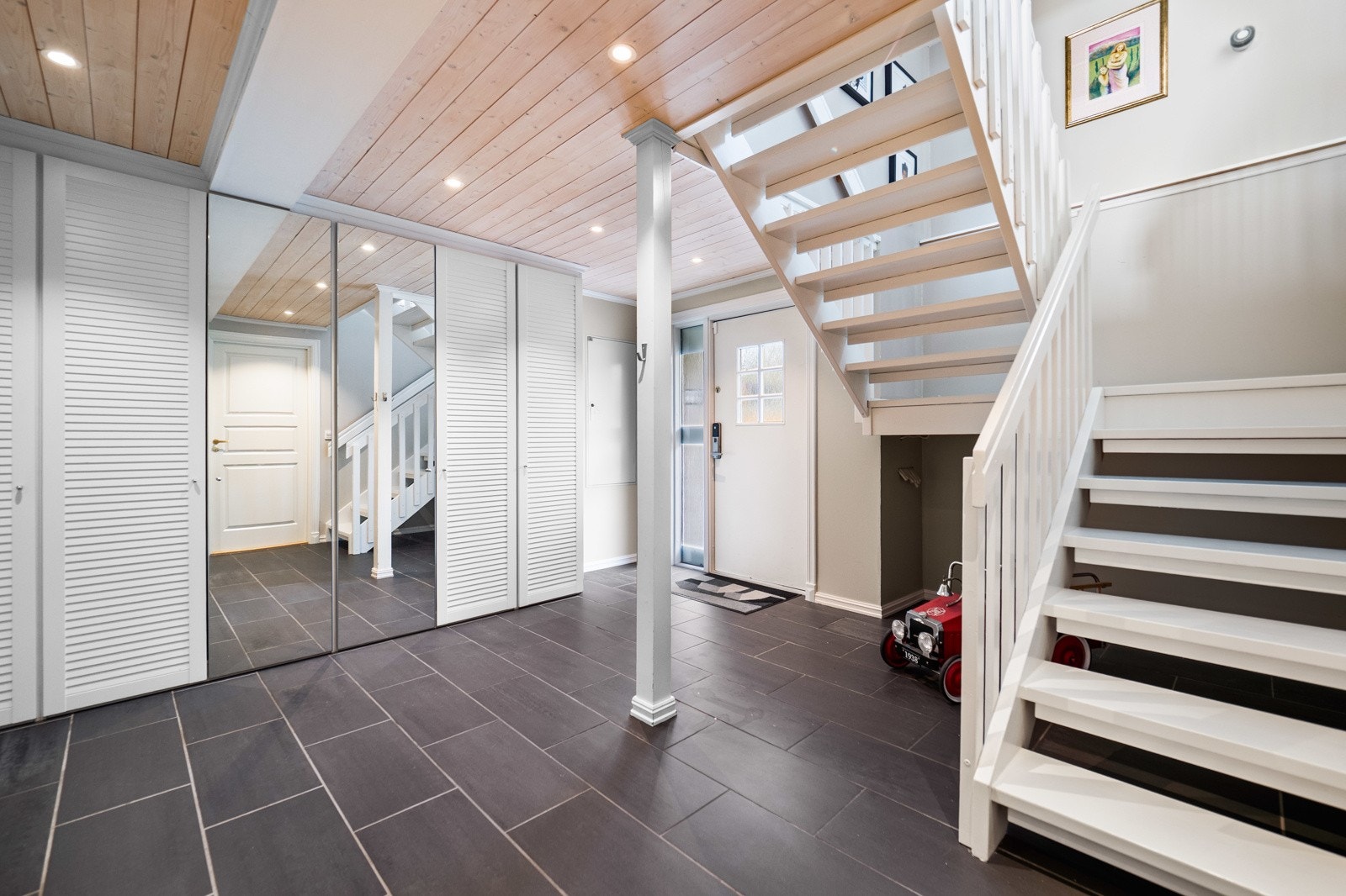 Hallen i kjelleren er flislagt og innredet med en stor skyvedørsgarderobe. Det er også inngang til en bod. Galleribilde