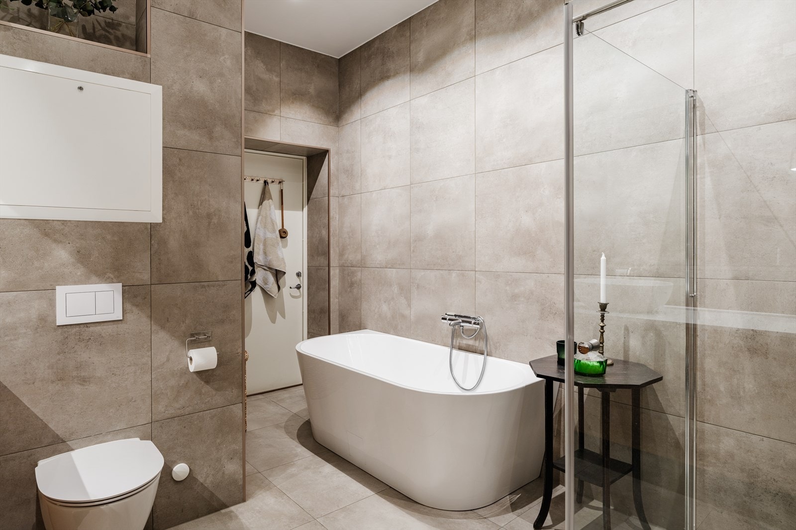 Badet er utstyrt med skål servant på kompositt benkeplate, dusj i hjørne med glassvegg /glassdør, frittstående badekar samt opplegg for vaskemaskin. Galleribilde